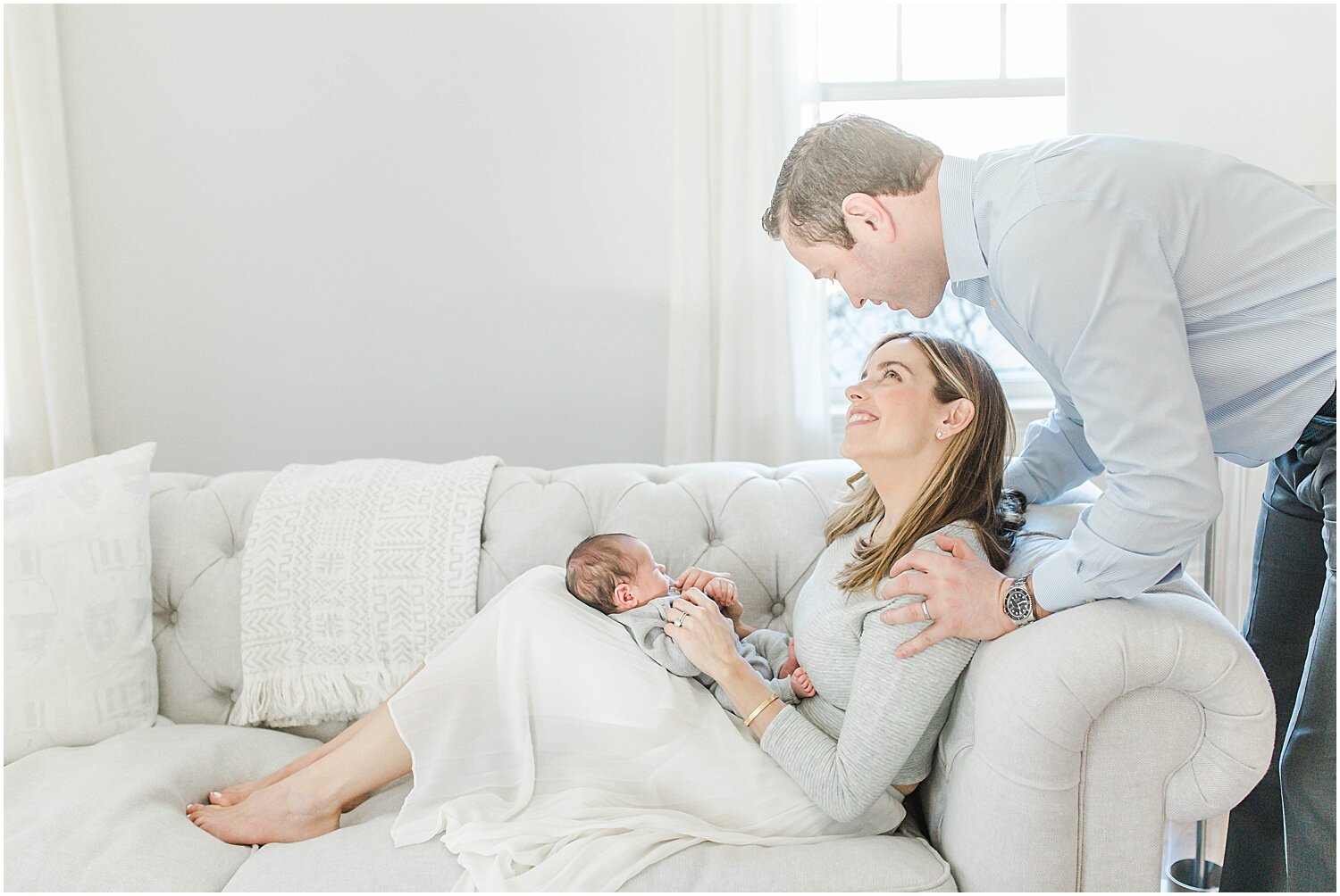 Parents and baby on couch in beautifully lit home in Westport, CT. Photos by Westport Newborn Photographer, Kristin Wood Photography.