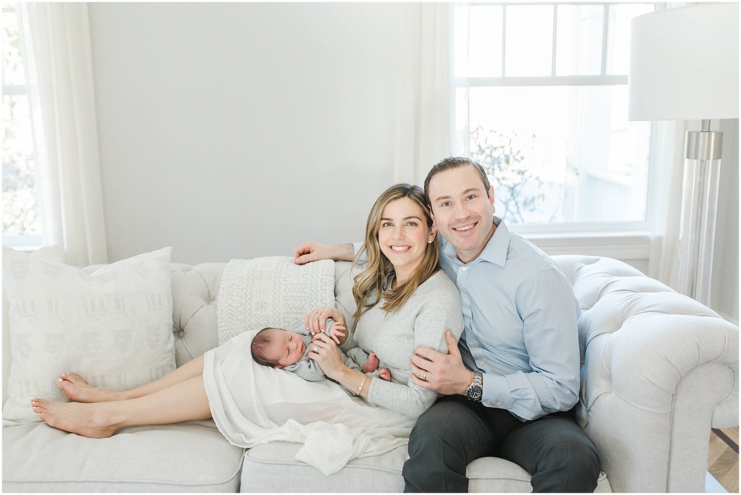 Parents and baby on couch in beautifully lit home in Westport, CT. Photos by Westport Newborn Photographer, Kristin Wood Photography.
