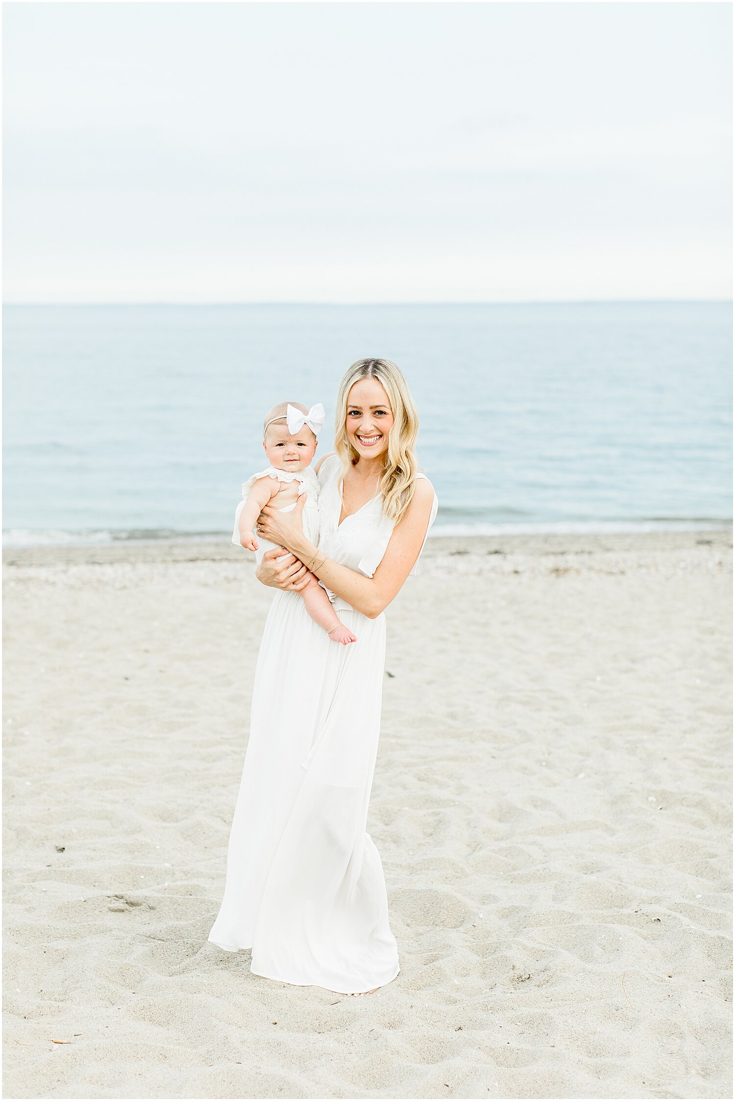 Mama with baby girl at 6 month milestone session on the beach in Westport, CT. Photos by Kristin Wood Photography.