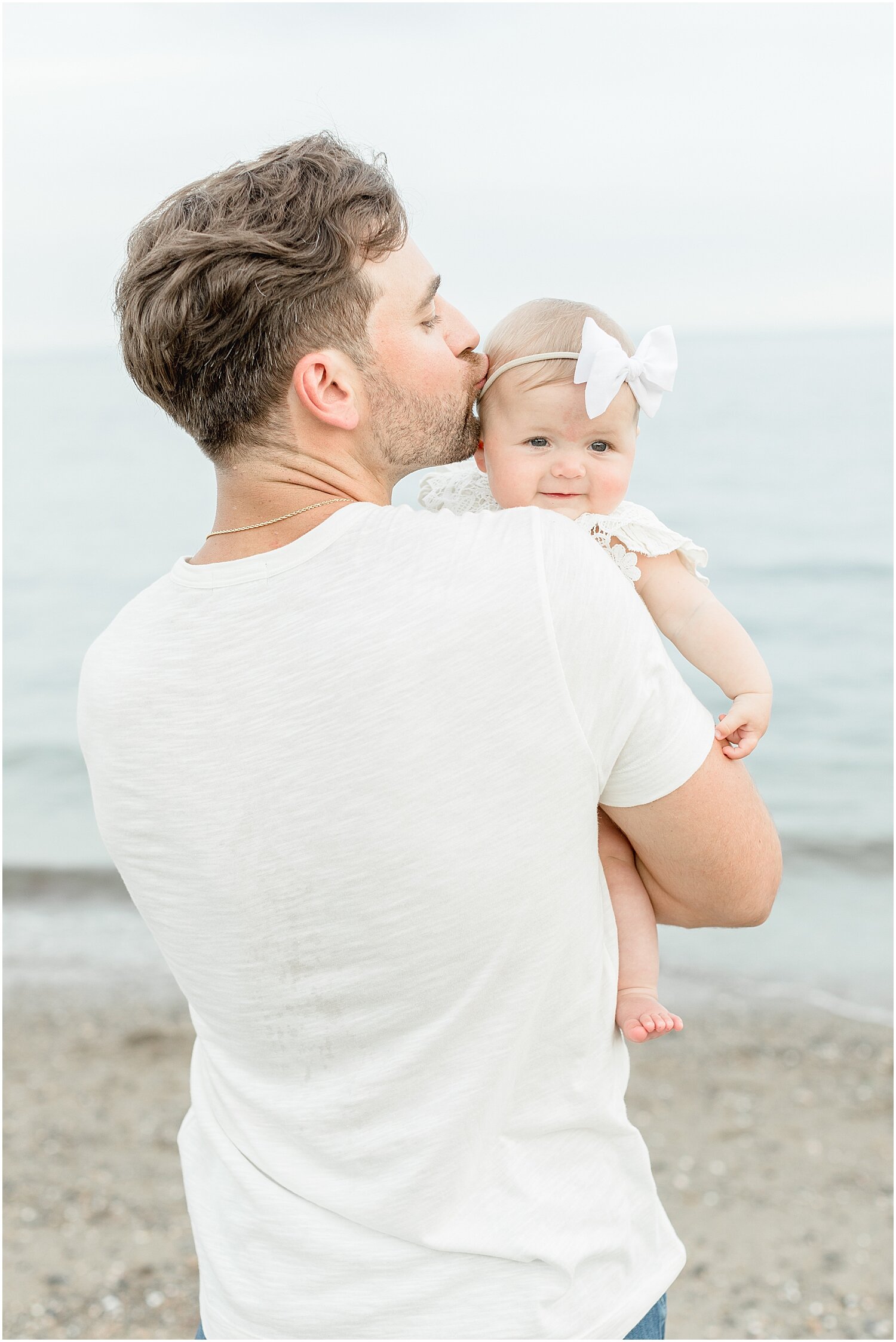 Dad with baby girl at 6 month milestone session on the beach in Westport, CT. Photos by Kristin Wood Photography.