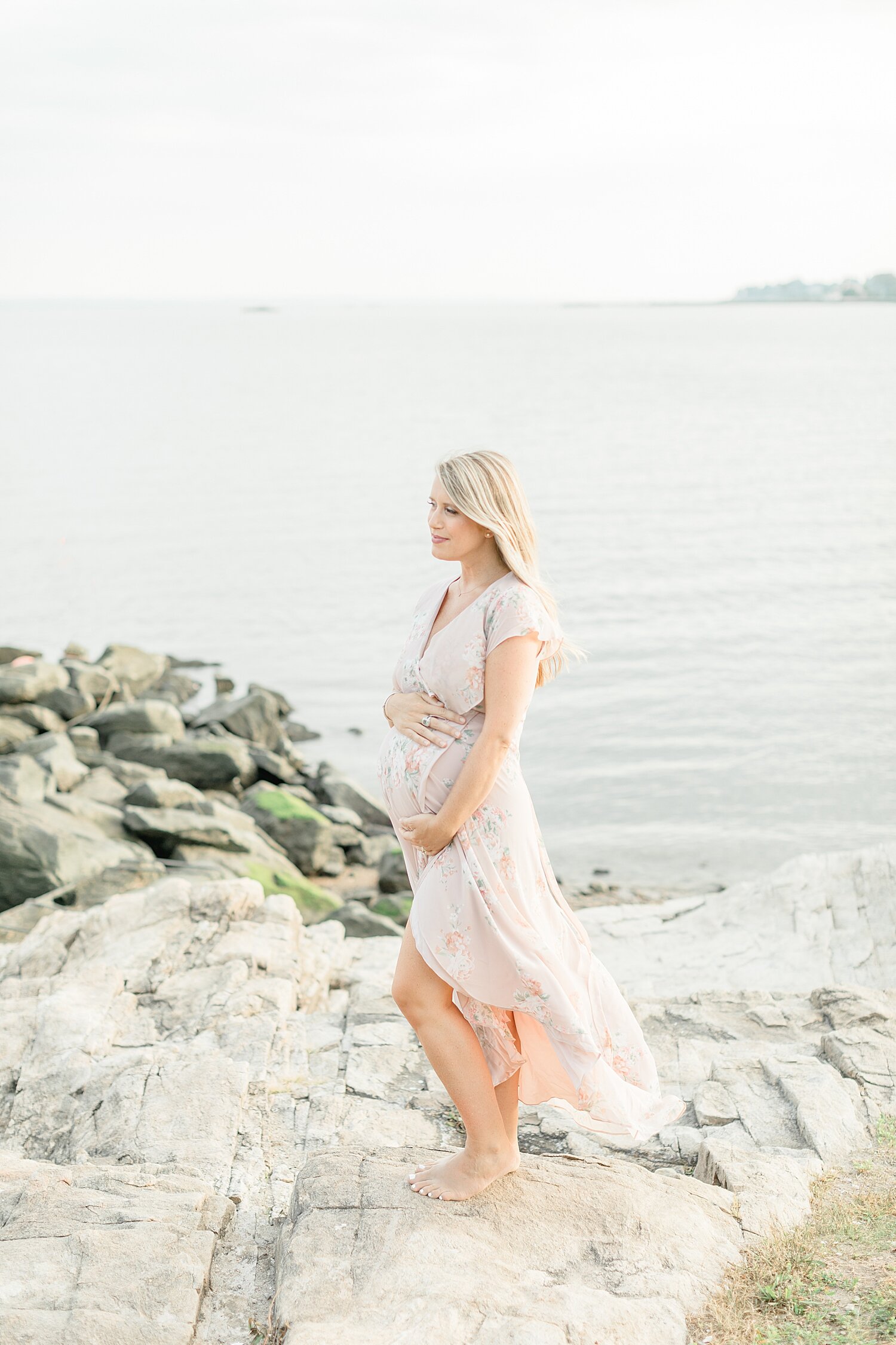 Mama on the rocks at Weed Beach in Darien, CT during maternity photoshoot with Kristin Wood Photography.