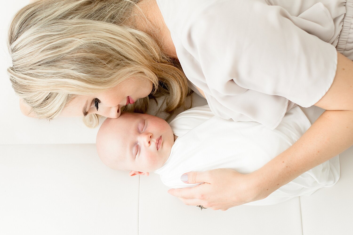 Mom laying on bed with baby girl. Photos by Kristin Wood Photography. 