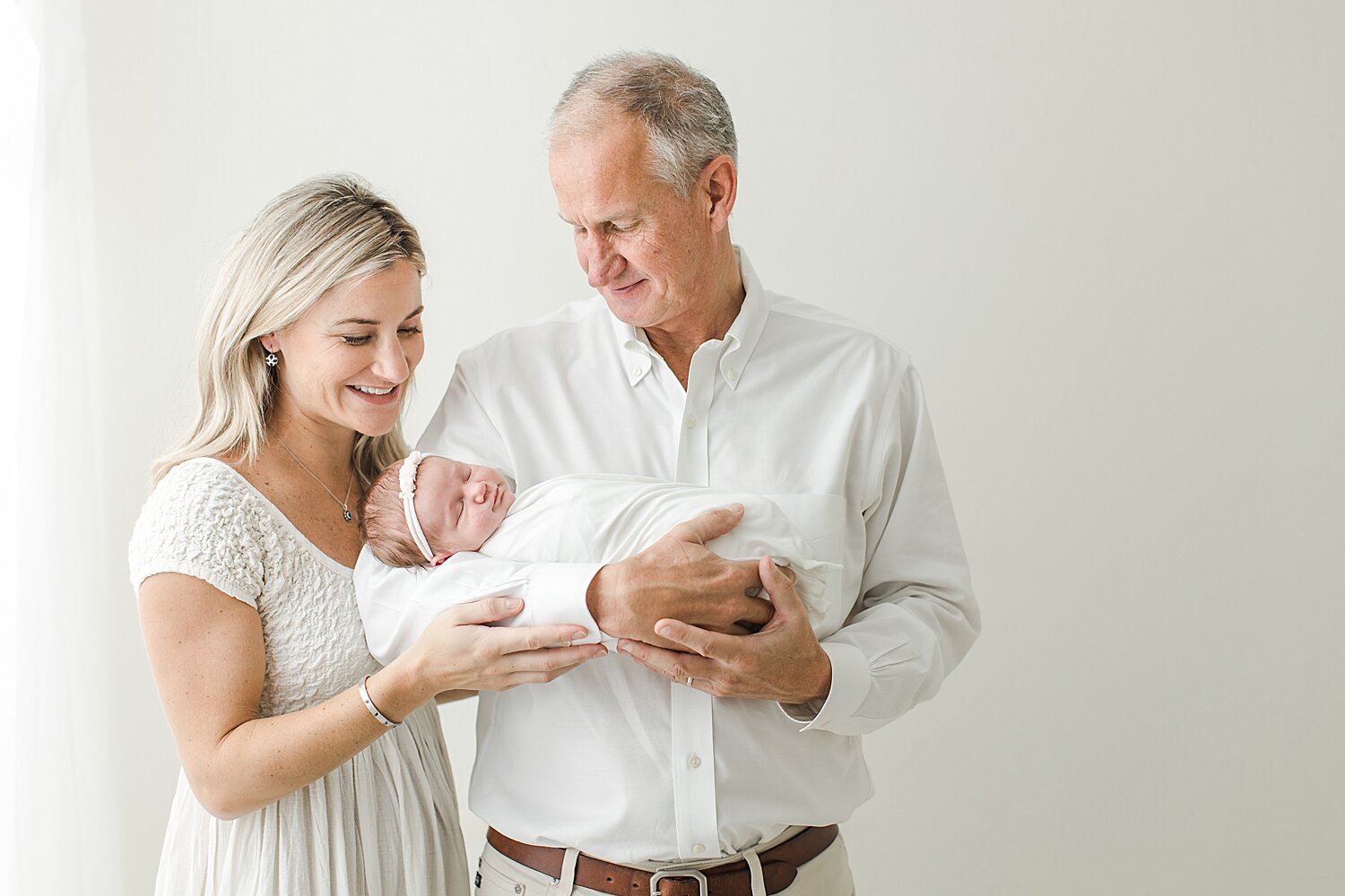 Mom and dad adoring their baby girl during newborn photoshoot in a newborn studio in Darien, CT. Photos by Kristin Wood Photography. 