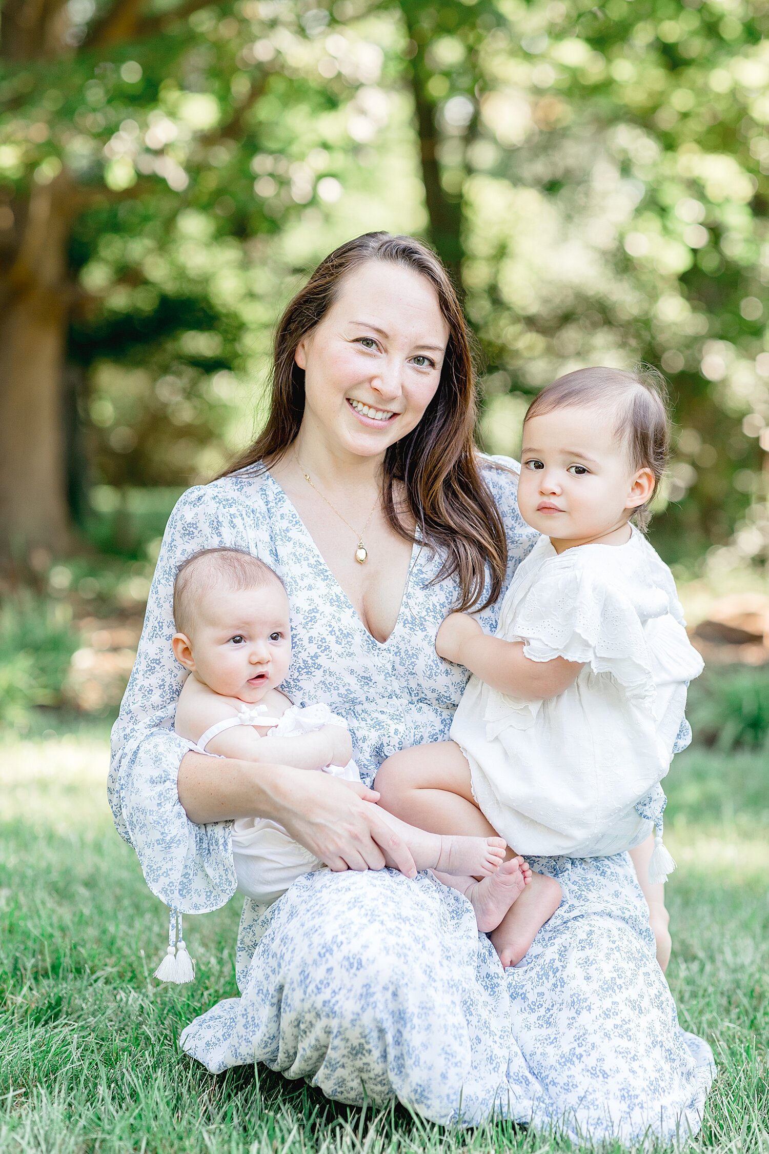 Mom with her two girls during family newborn photoshoot outside in Darien, CT with Kristin Wood Photography.