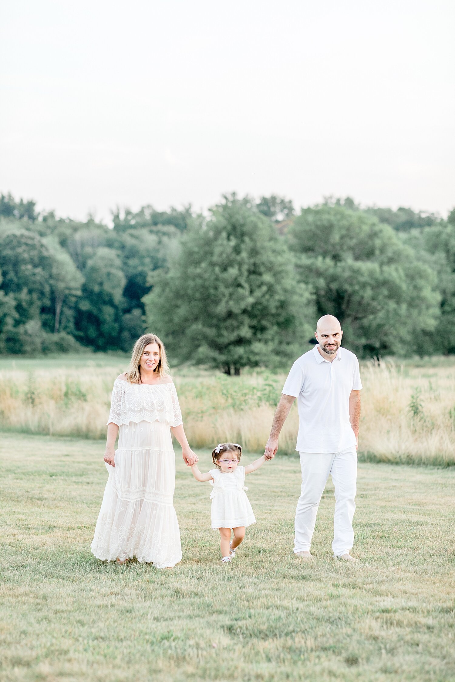 Family walking through the field at Waveny Park in Darien, CT. Maternity photos by Kristin Wood Photography.