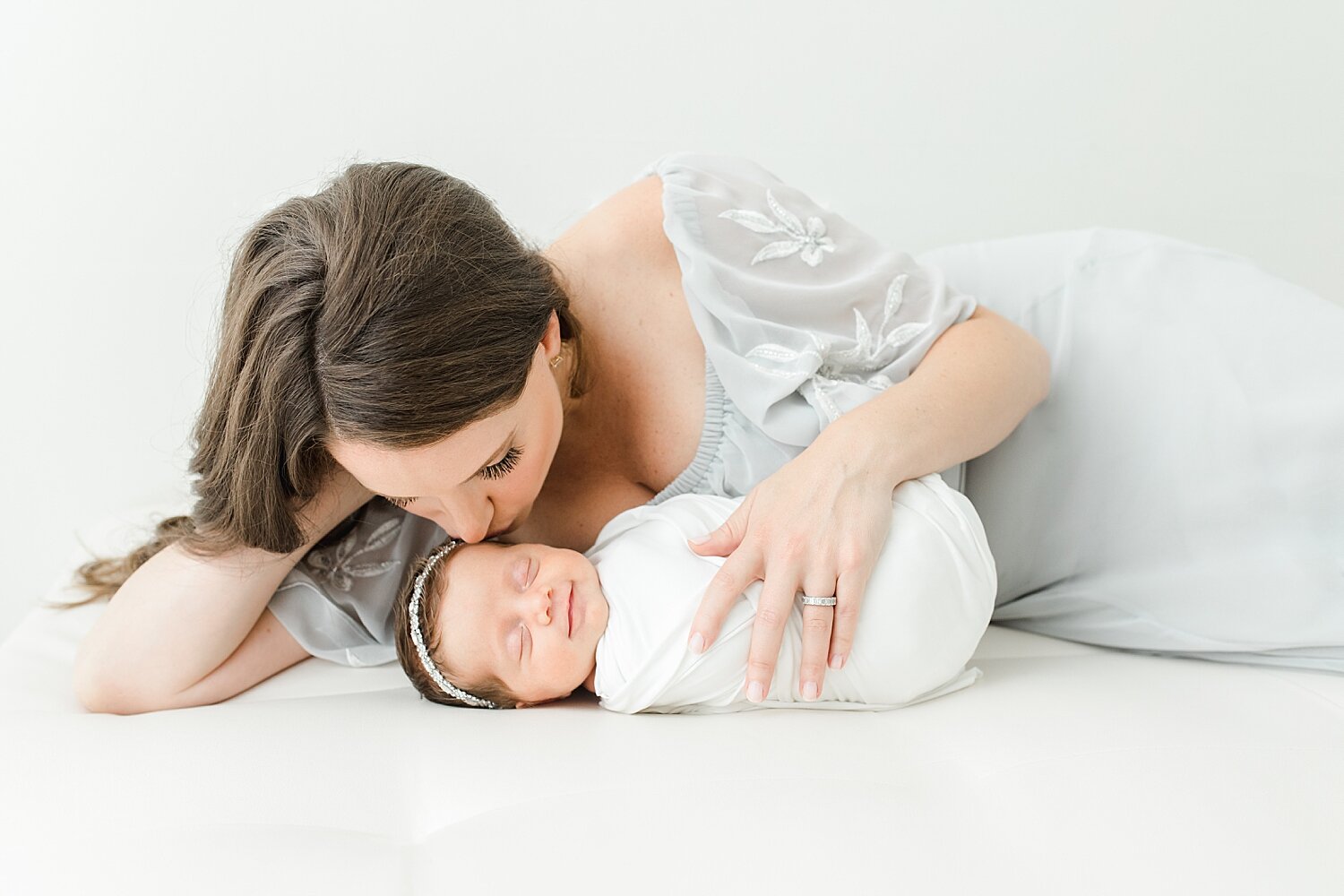 Mother and daughter laying on bed for photo during newborn session. Photos by Kristin Wood Photography.