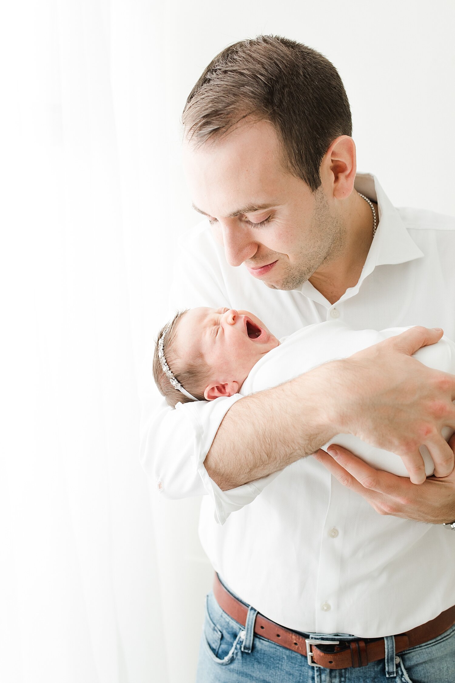 Dad with daughter during newborn photoshoot. Photos by Kristin Wood Photography.