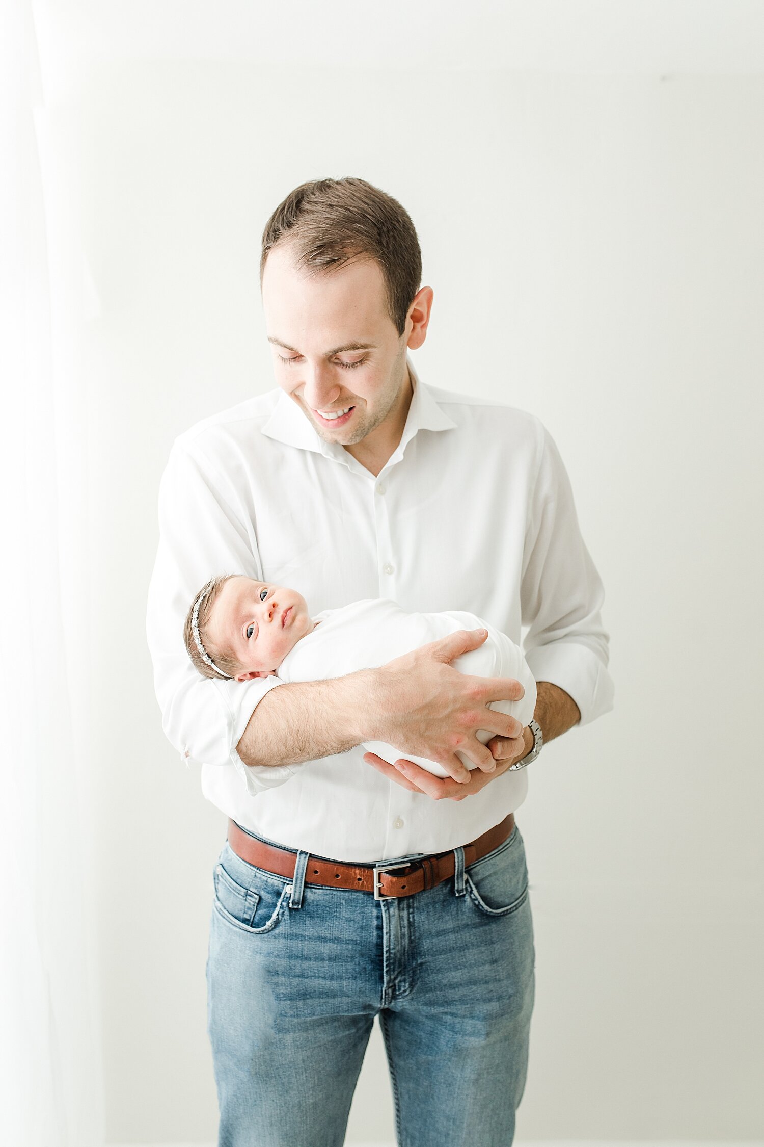 Dad with daughter during newborn photoshoot. Photos by Kristin Wood Photography.