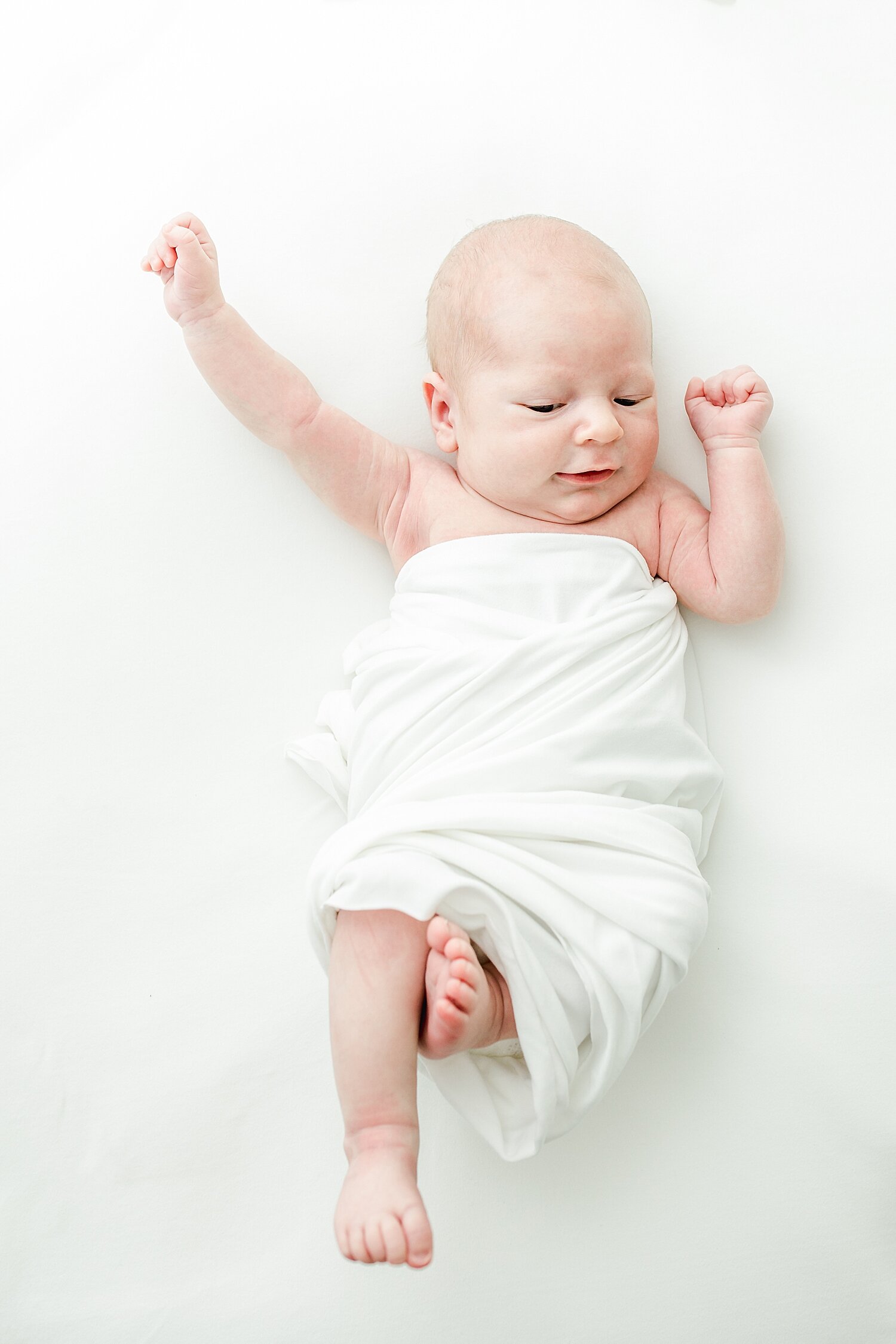 Photo of newborn stretched out on a white backdrop. Photos by Kristin Wood Photography.