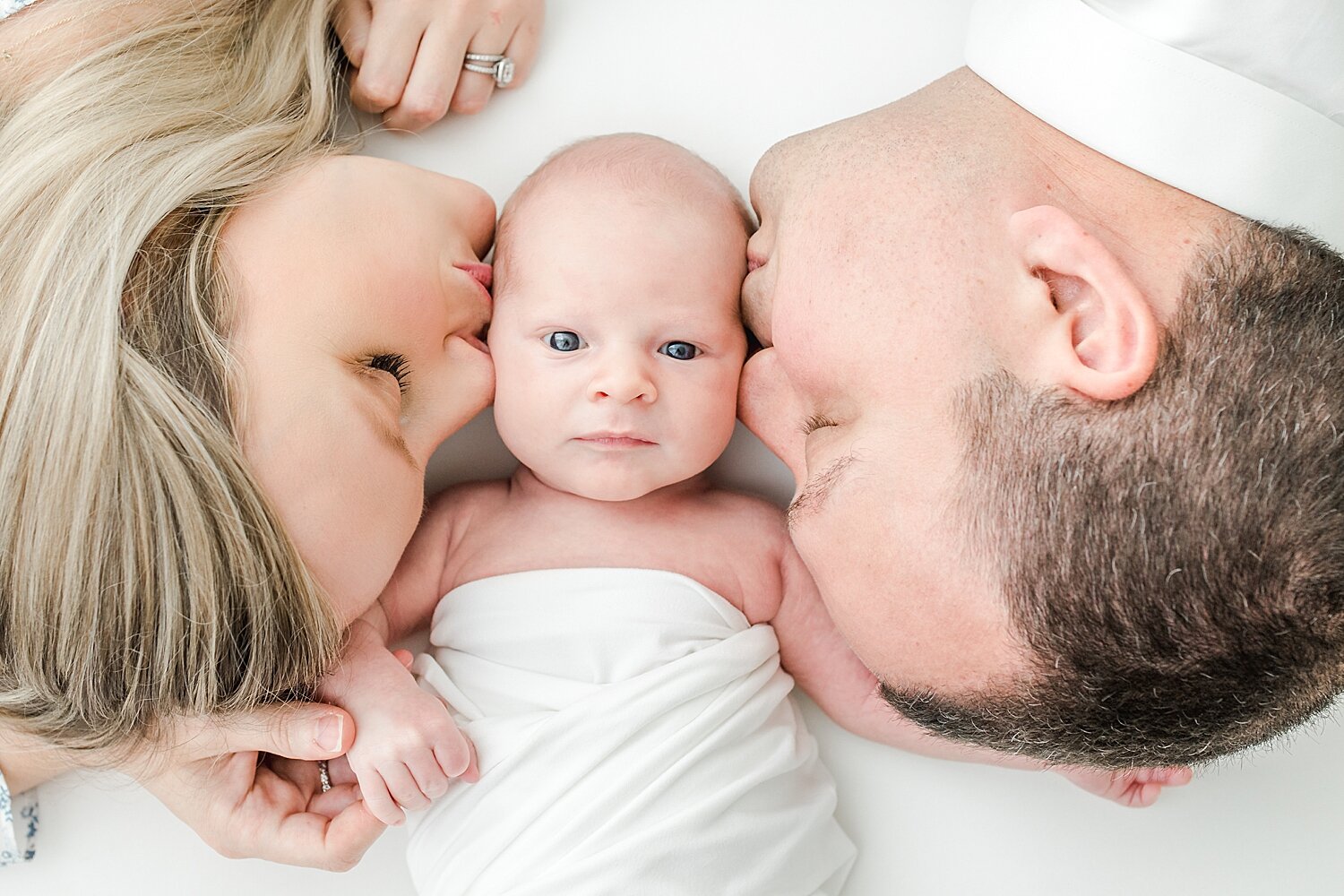 Mom and Dad giving their first born son a kiss during his newborn session in Darien, CT. Photos by Kristin Wood Photography.