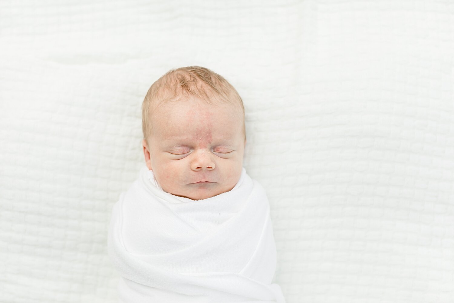 Baby boy swaddled on a white blanket | Kristin Wood Photography