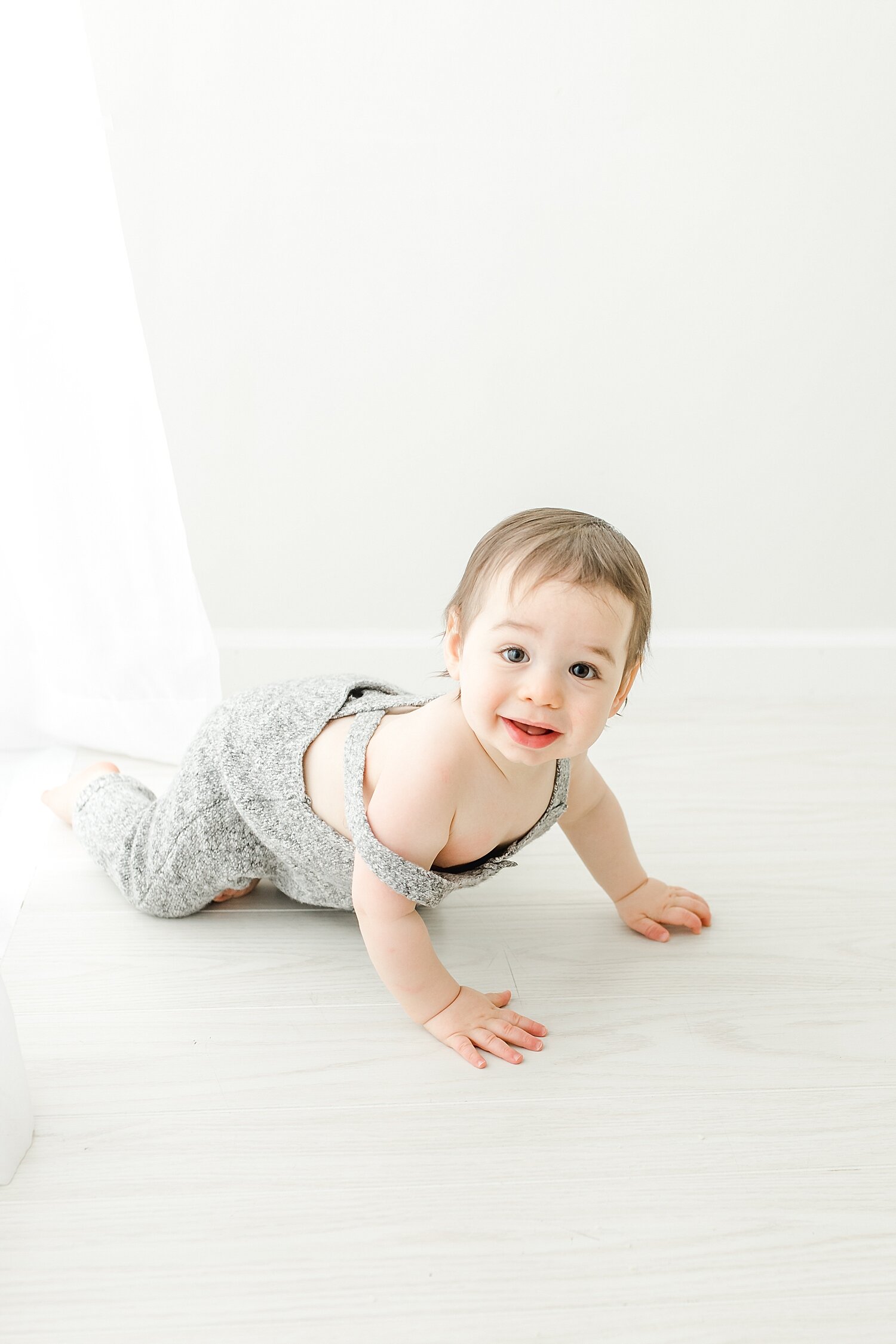 Little boy crawling by the curtains in photography studio in Darien, CT. Photos by Kristin Wood Photography.