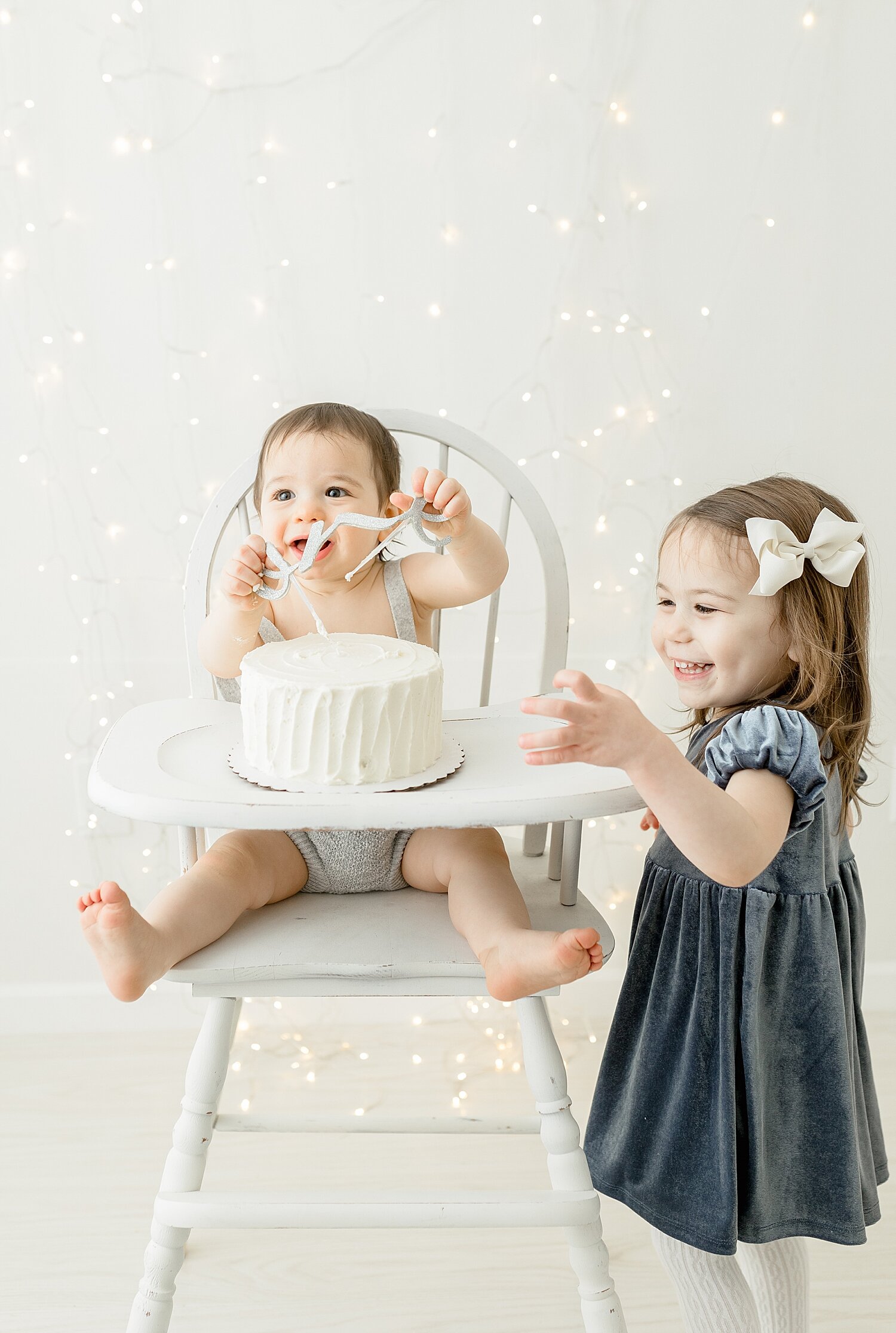 Big sister standing by her brother during cake smash photoshoot with Kristin Wood Photography.