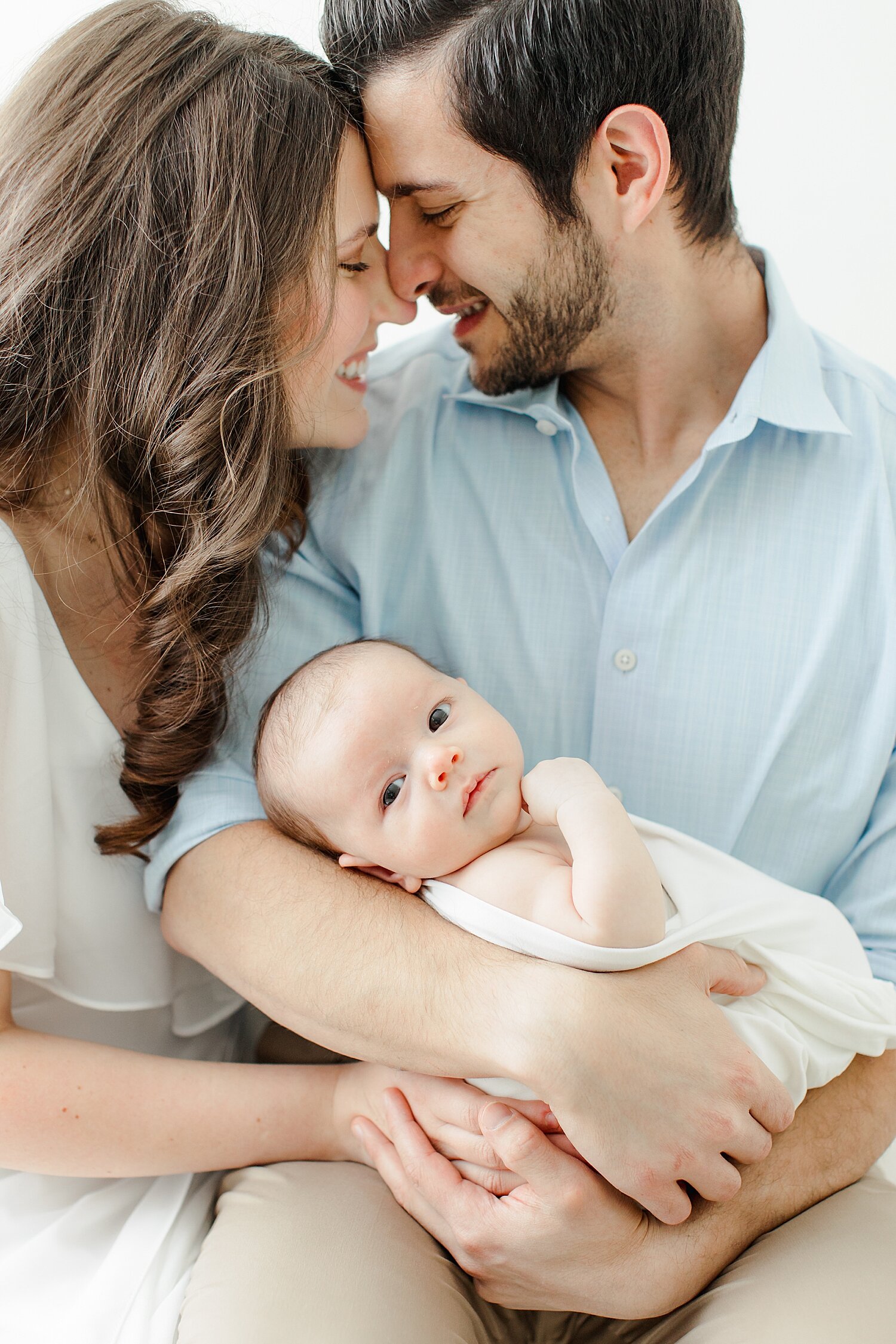 Mom and Dad looking at each other while holding their baby boy. Photos by Kristin Wood Photography.