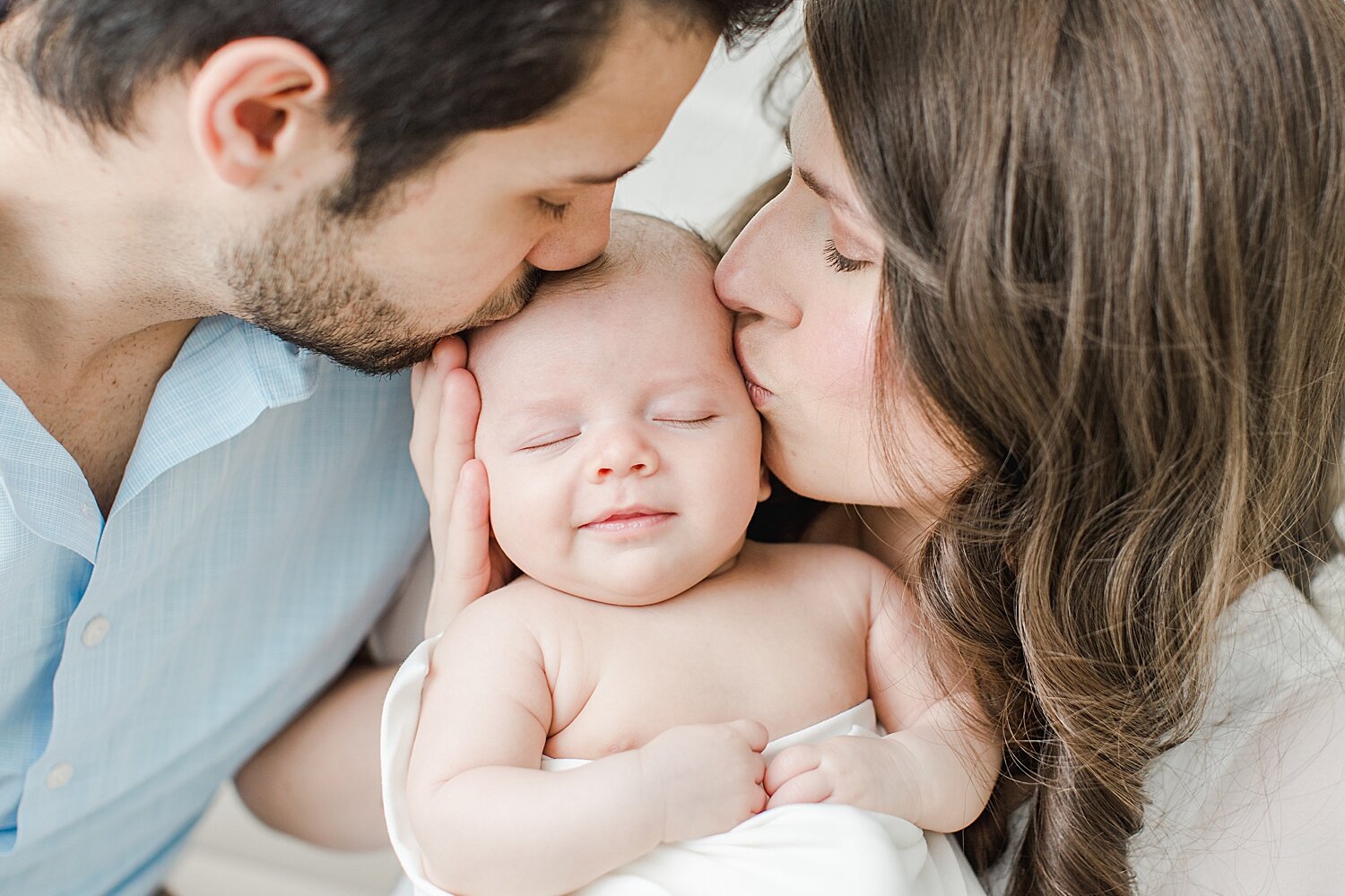 Mom and Dad kissing baby boy during newborn session with Kristin Wood Photography.