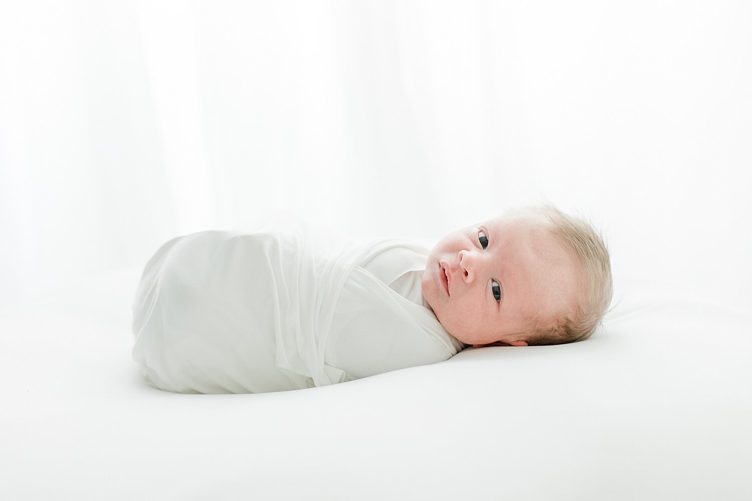 Backlit photo of newborn swaddled for newborn session. Photos by Fairfield County Photographer, Kristin Wood Photography.