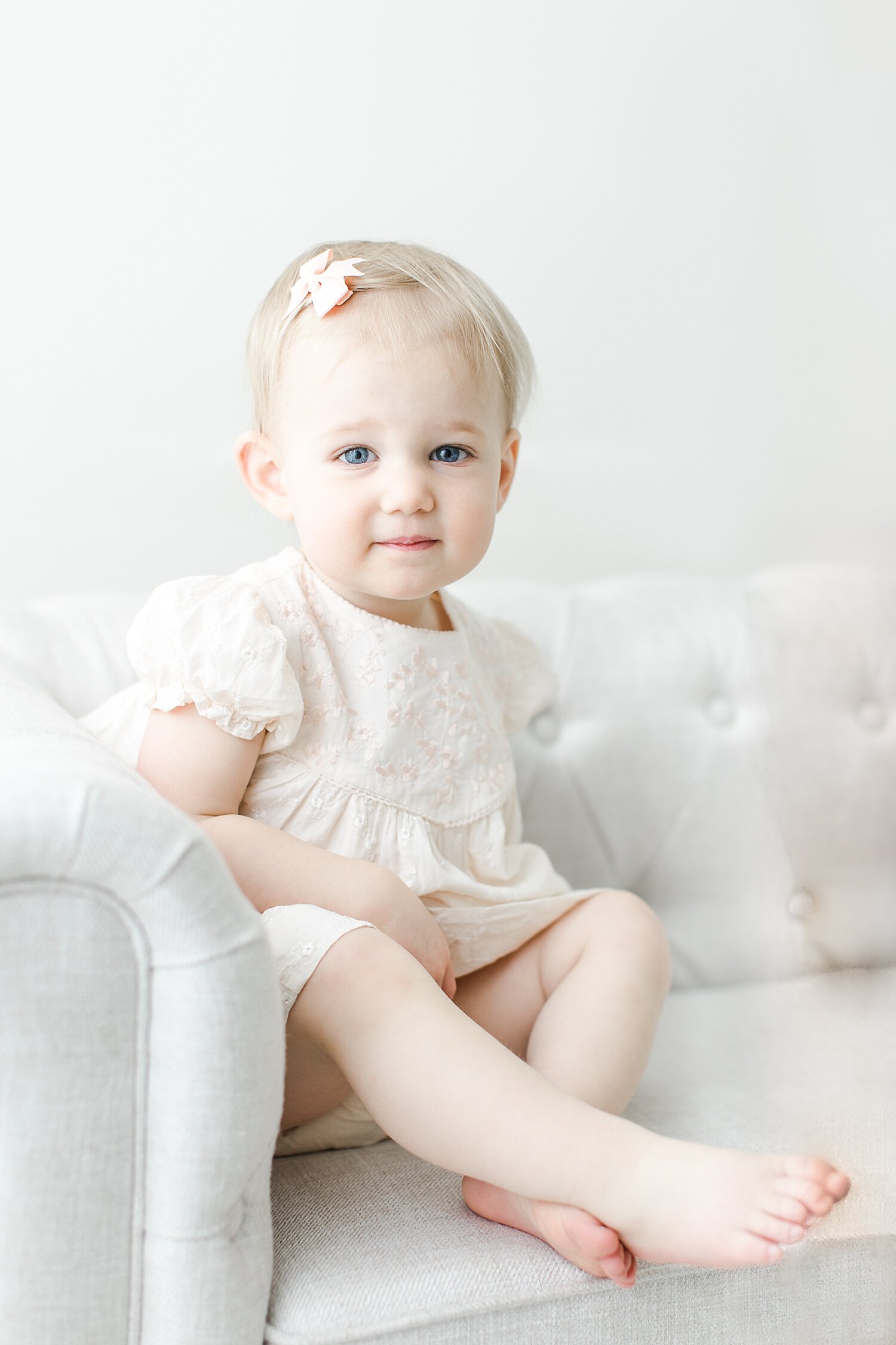 18 month old little girl sitting on a couch for photos with Kristin Wood Photography.