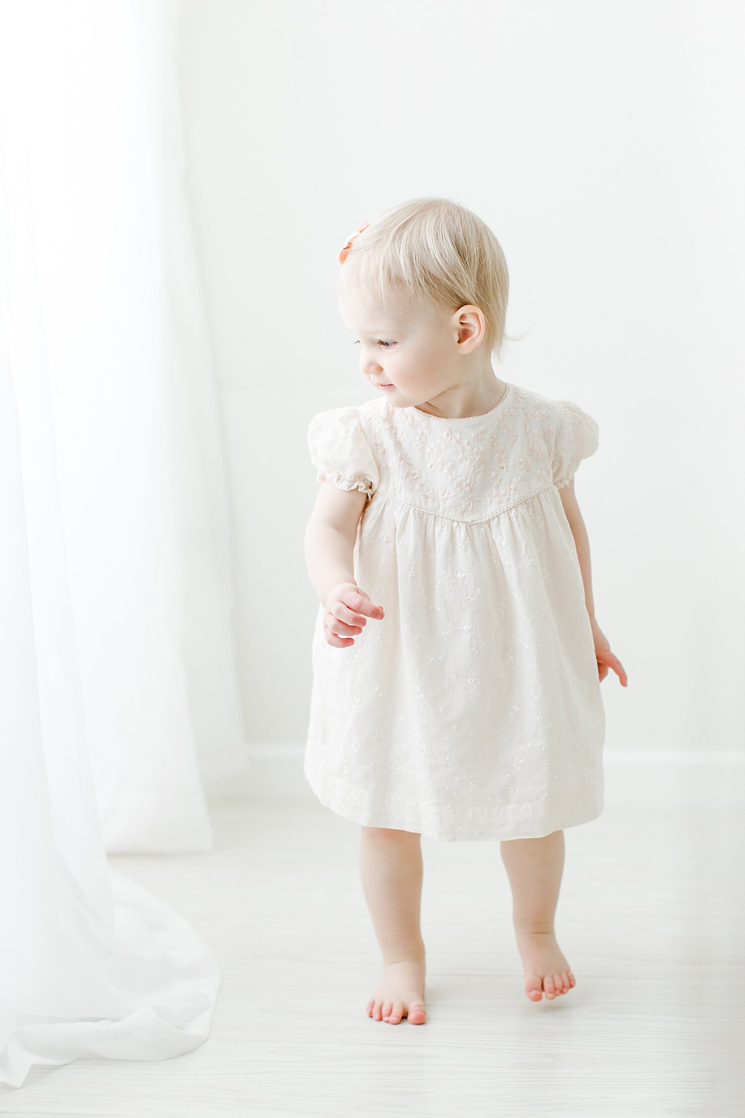 Toddler standing by window in studio for milestone photos with Kristin Wood Photography.