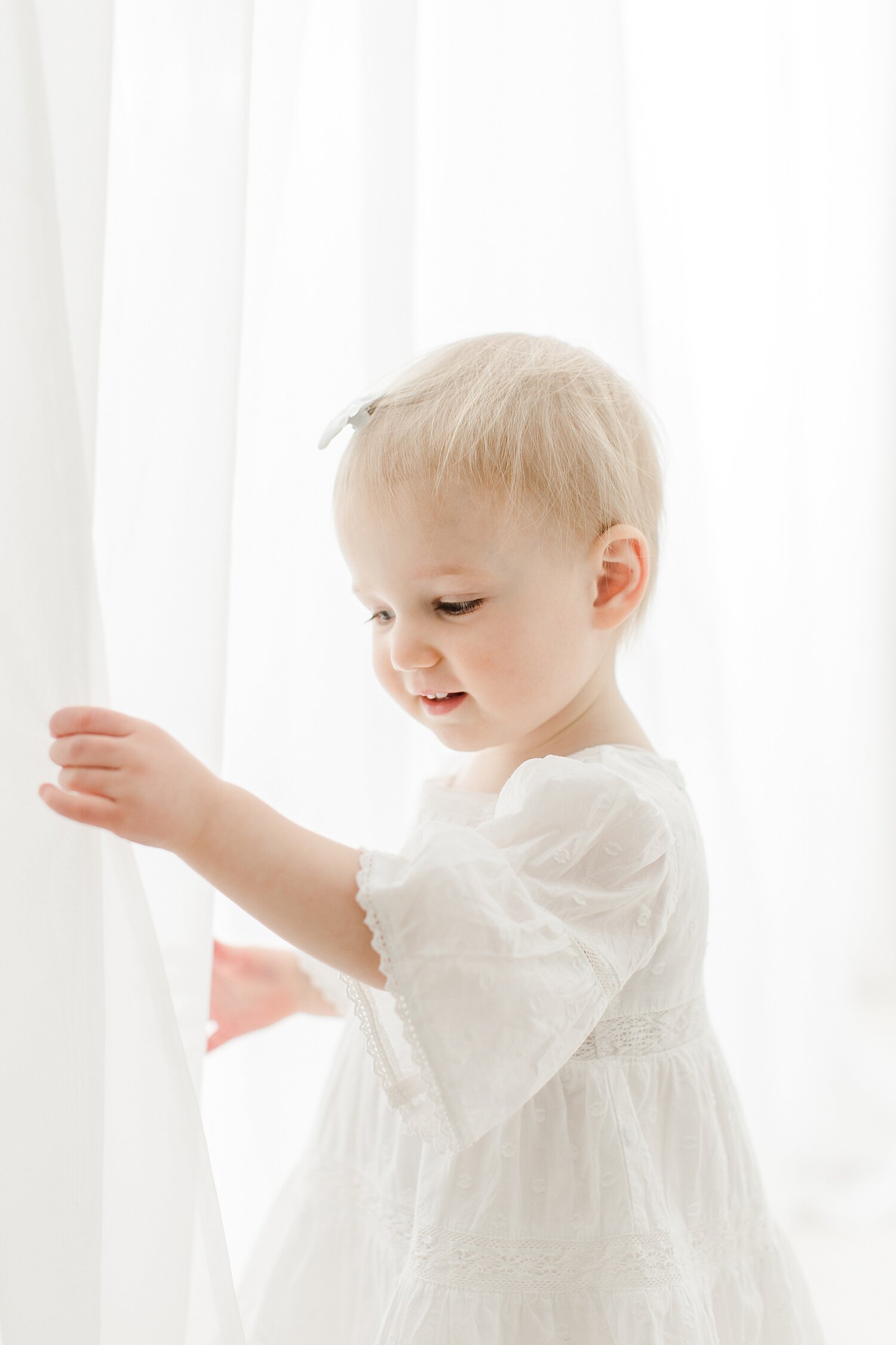Toddler playing in sheer curtains in studio in Westport, CT. Photo by Kristin Wood Photography.