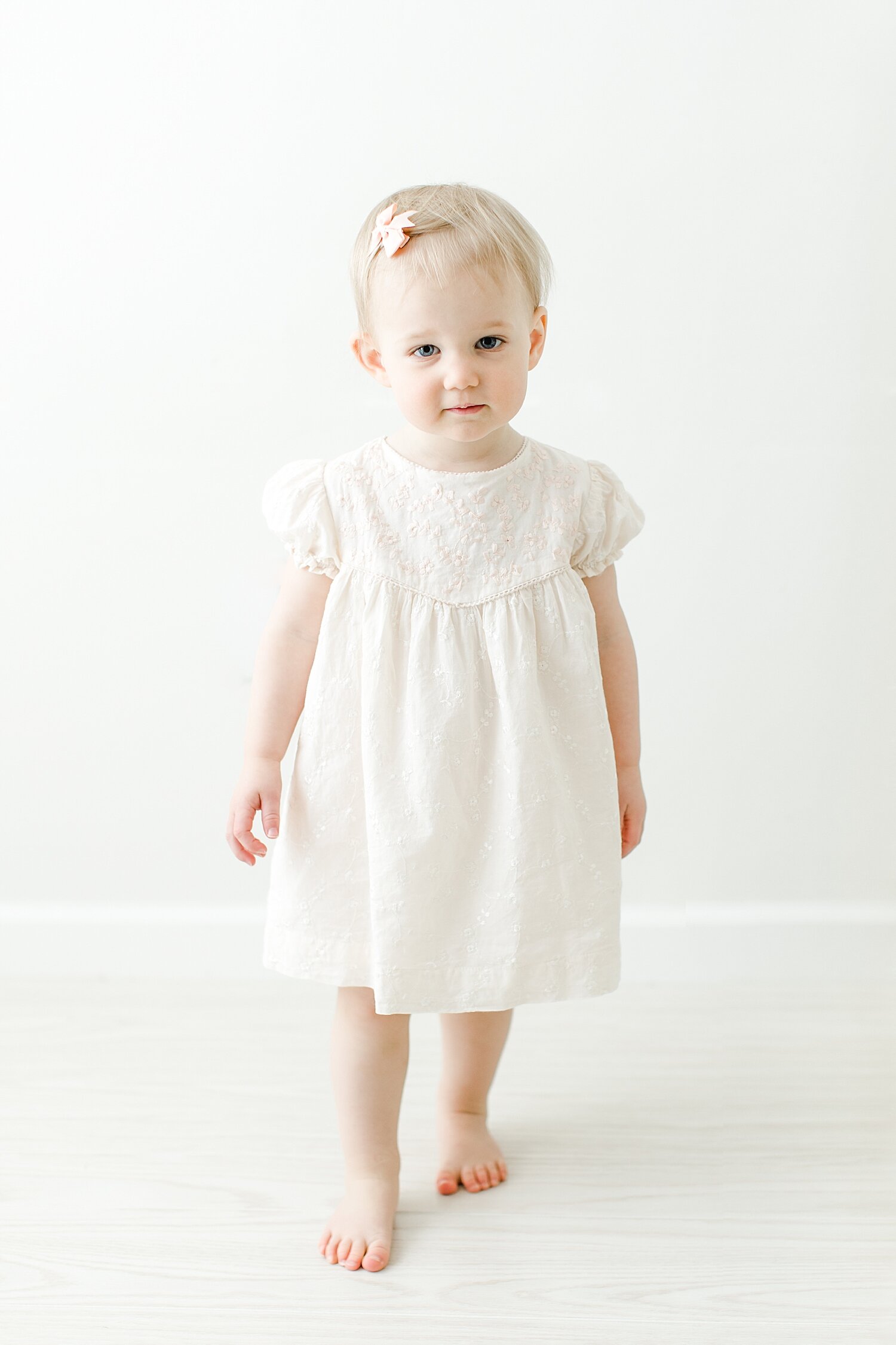 18 month old standing in a soft pink eyelet dress. Photo by Kristin Wood Photography.