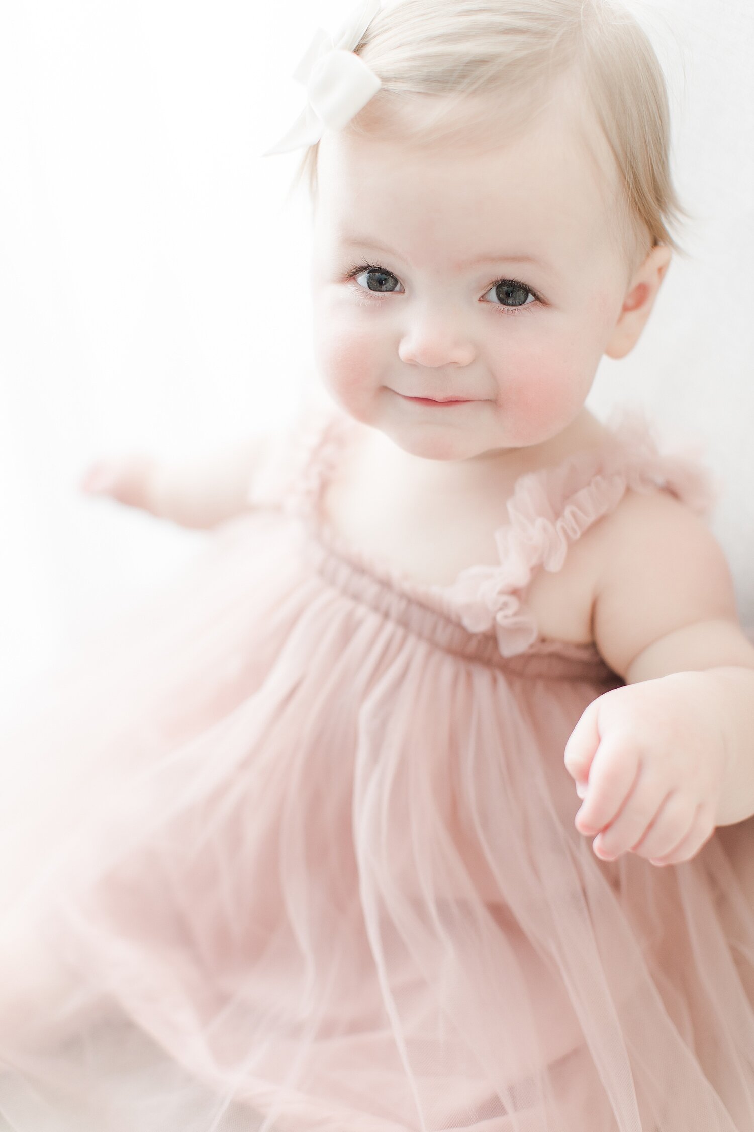 Baby girl in a blush dress for birthday photos with Kristin Wood Photography.