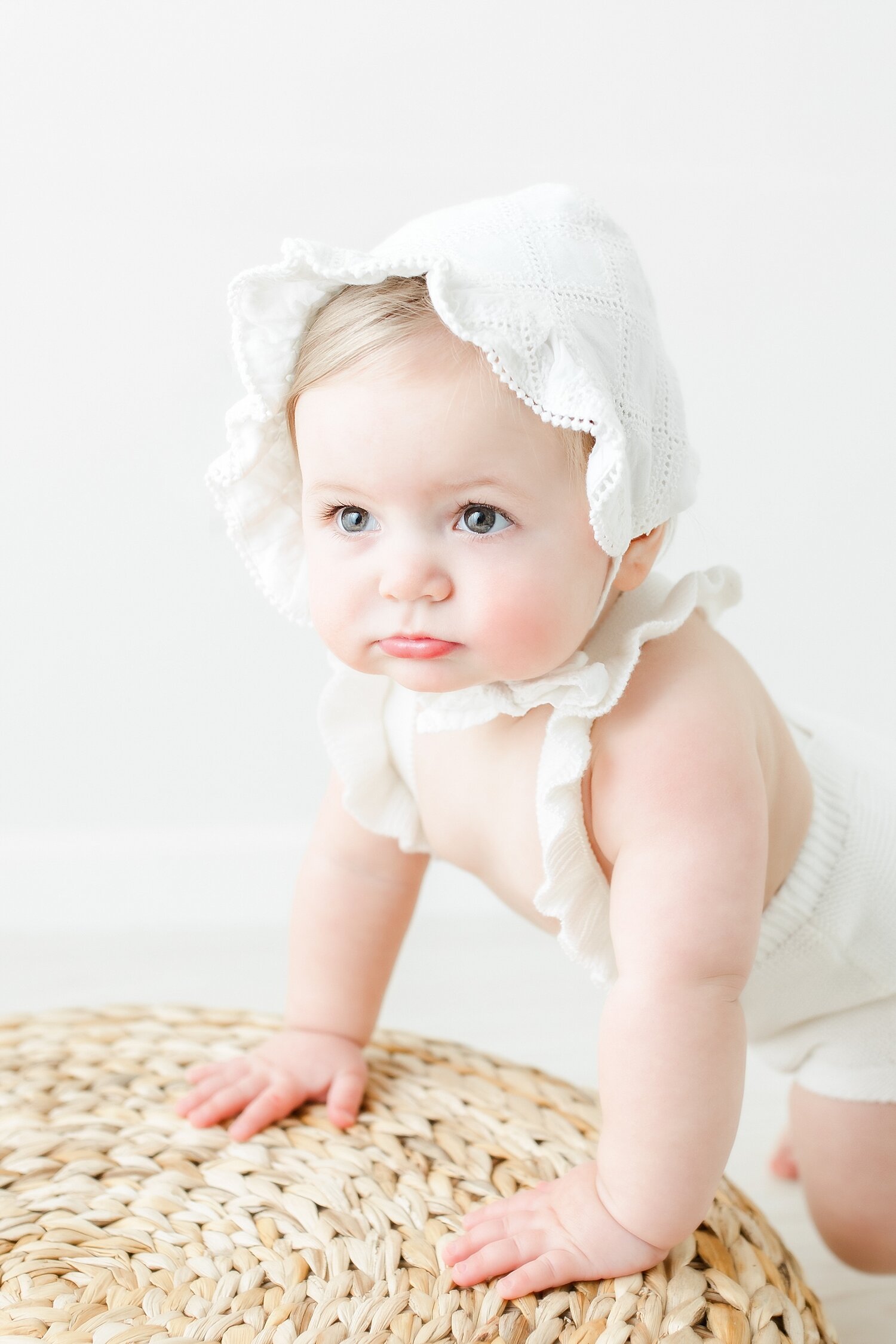 Baby girl wearing a white bonnet for her birthday photos with Kristin Wood Photography