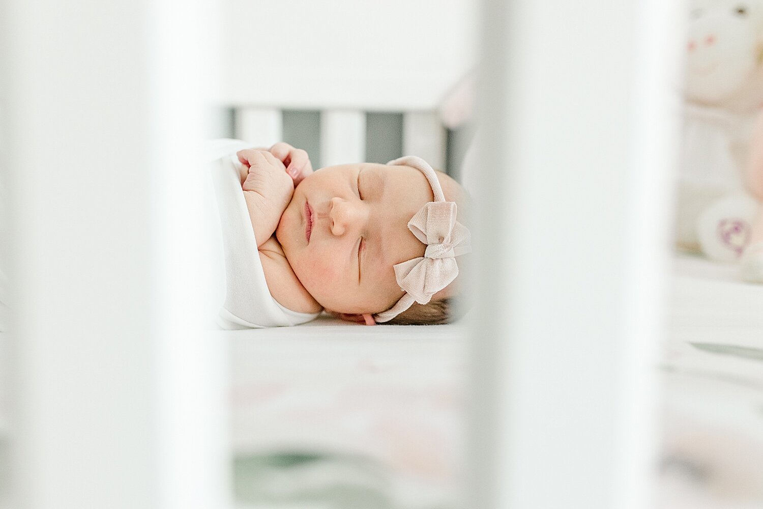 Newborn baby girl laying in crib on floral sheet. Photo by Kristin Wood Photography.