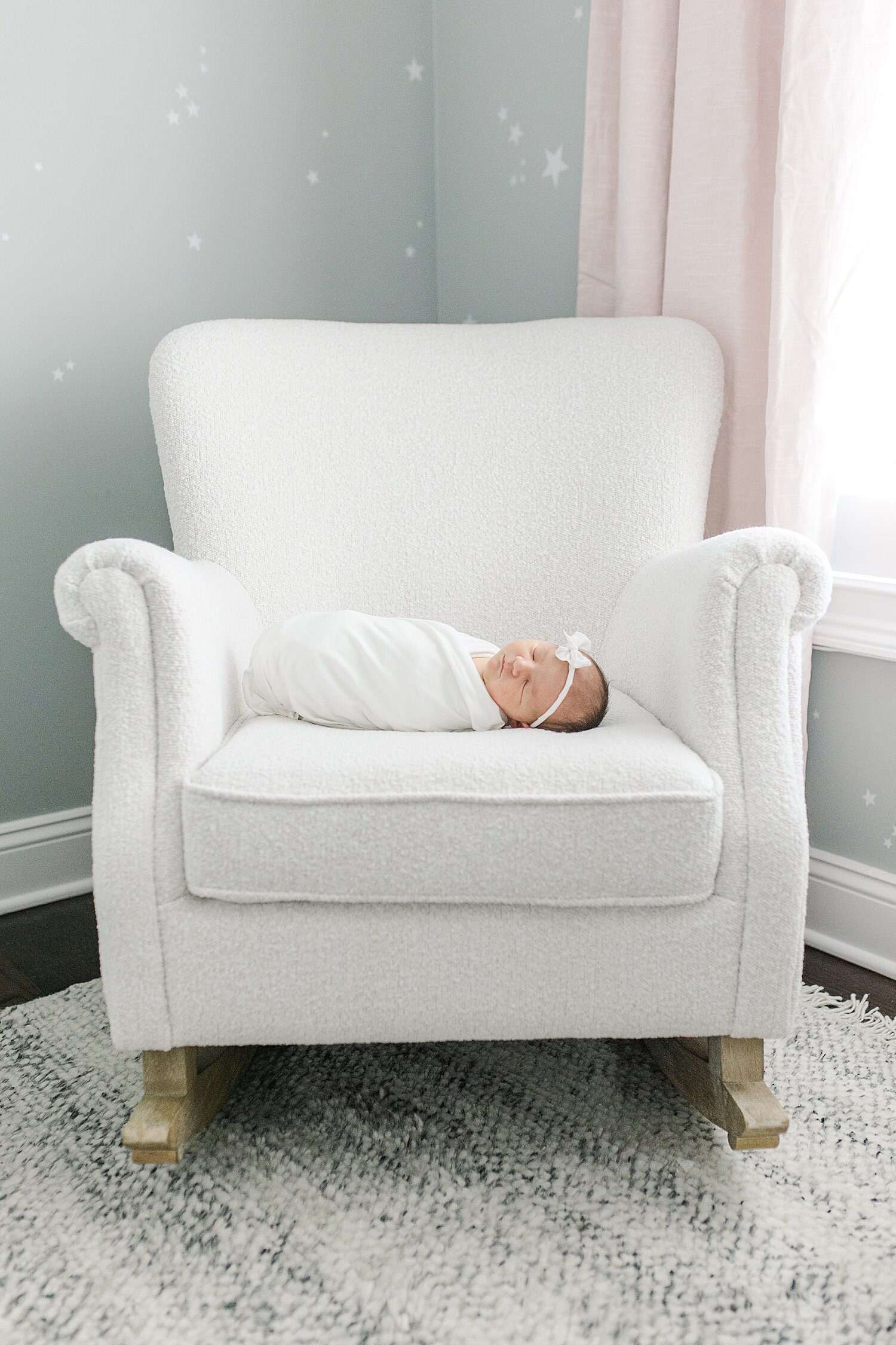 Newborn laying on chair in nursery. Photo by Kristin Wood Photography.