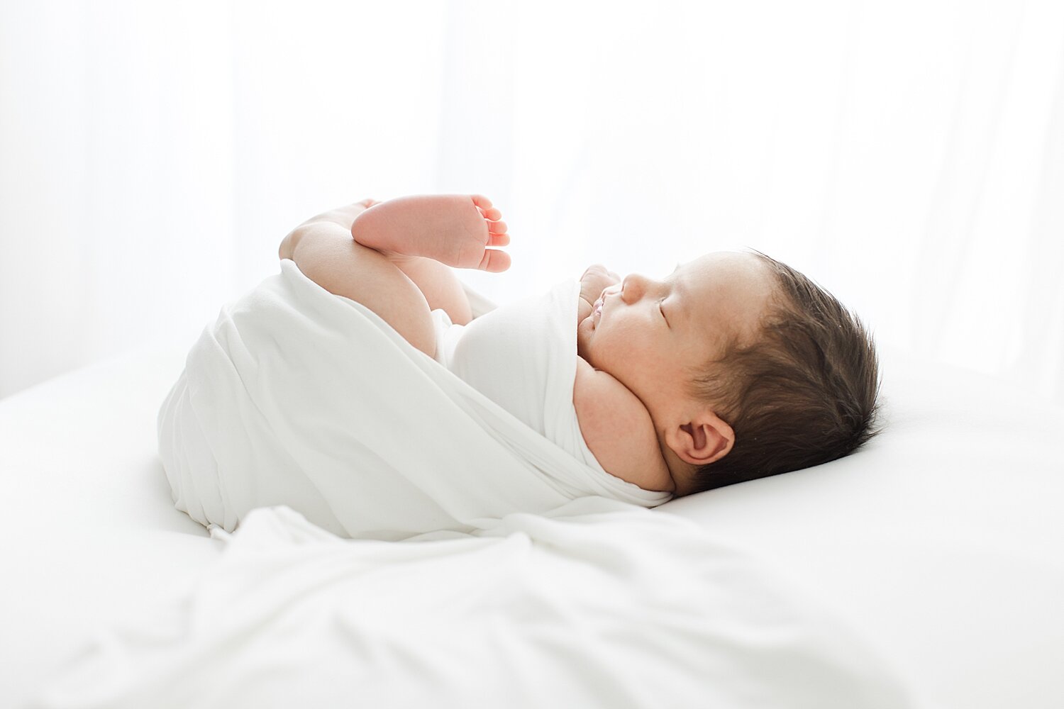 Classic newborn photo of baby swaddled in white. Photo by Kristin Wood Photography.