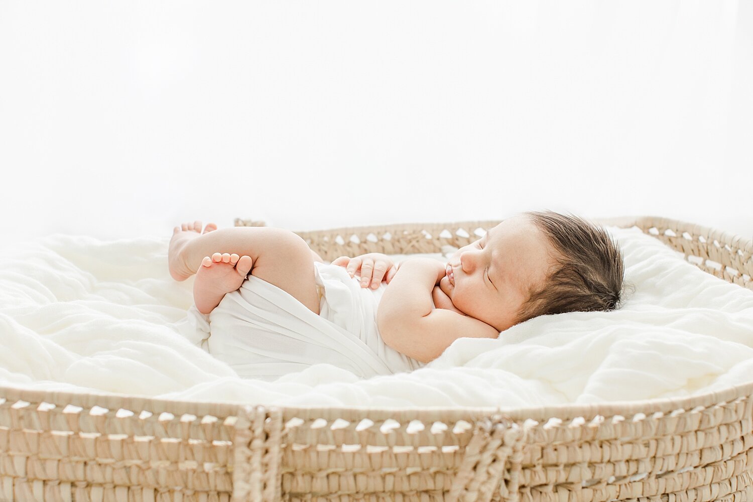 Baby boy laying in a Moses basket for newborn photos with Kristin Wood Photography.