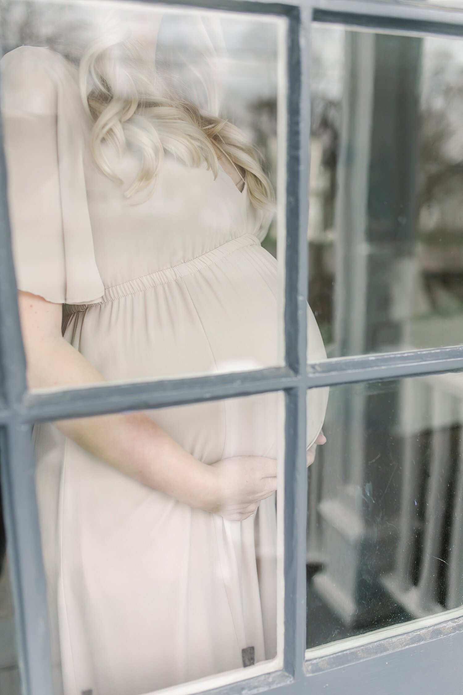 Pregnancy photoshoot in home. Photographer, Kristin Wood Photography, takes photo from outside the door.