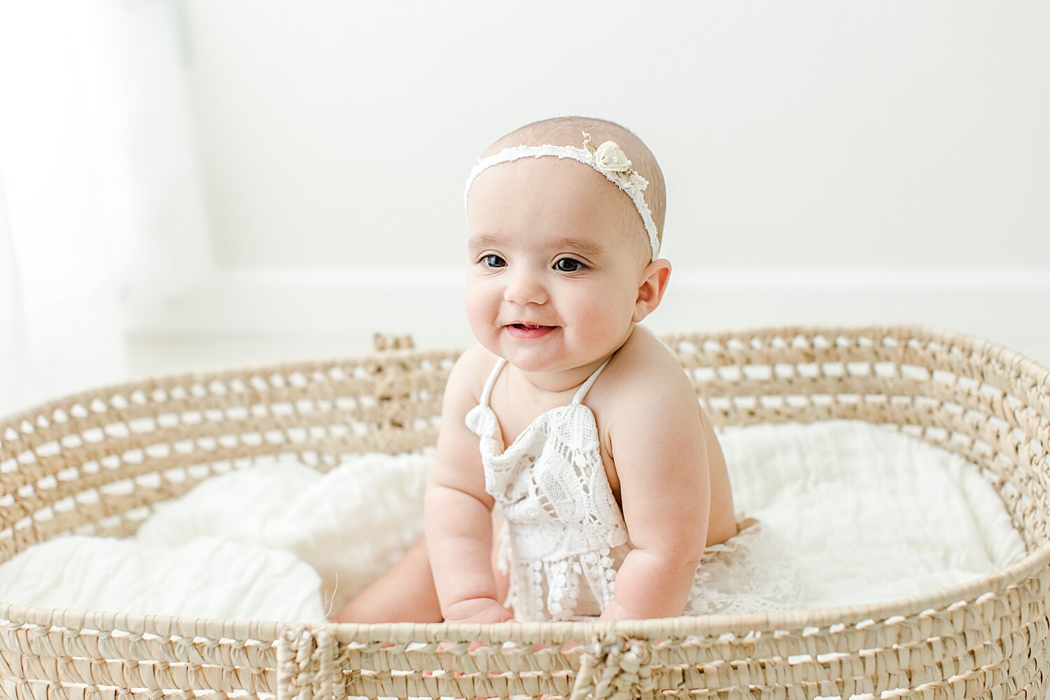 Eight month old baby girl sitting in Moses Basket for milestone photos with Kristin Wood Photography.