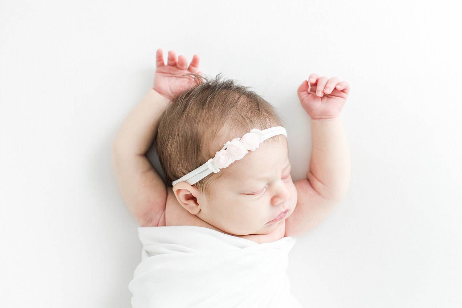 Baby girl with arms up by her head. Photo by Kristin Wood Photography.