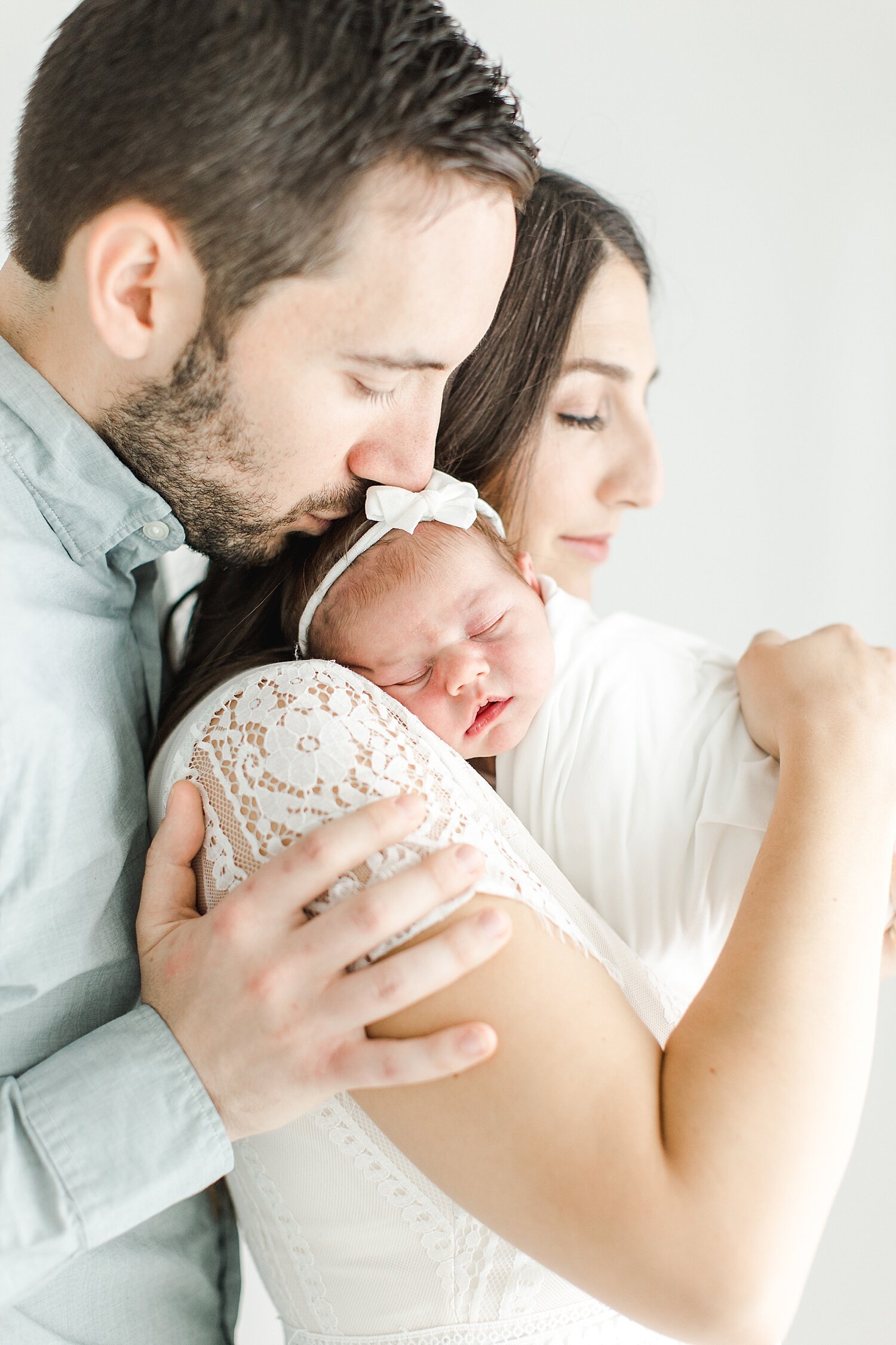 Studio newborn photo of Mom, Dad and their daughter. Photo by Kristin Wood Photography.