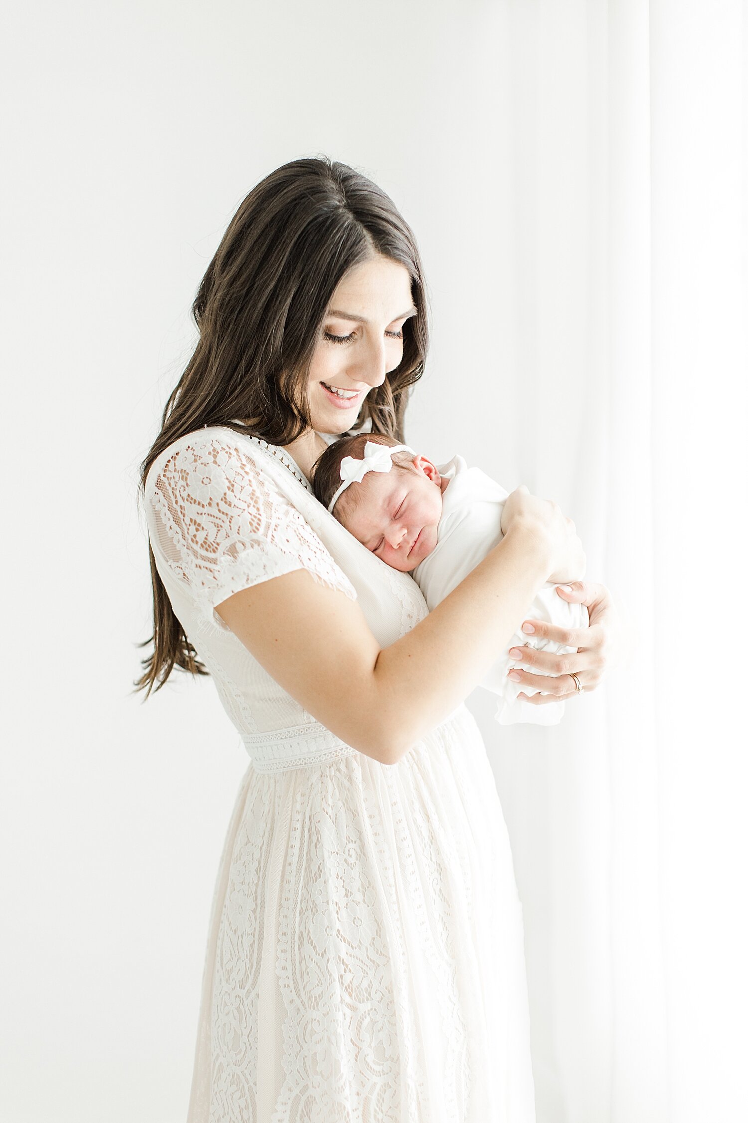 New mom holding her daughter for newborn photos in Westport studio with Kristin Wood Photography.