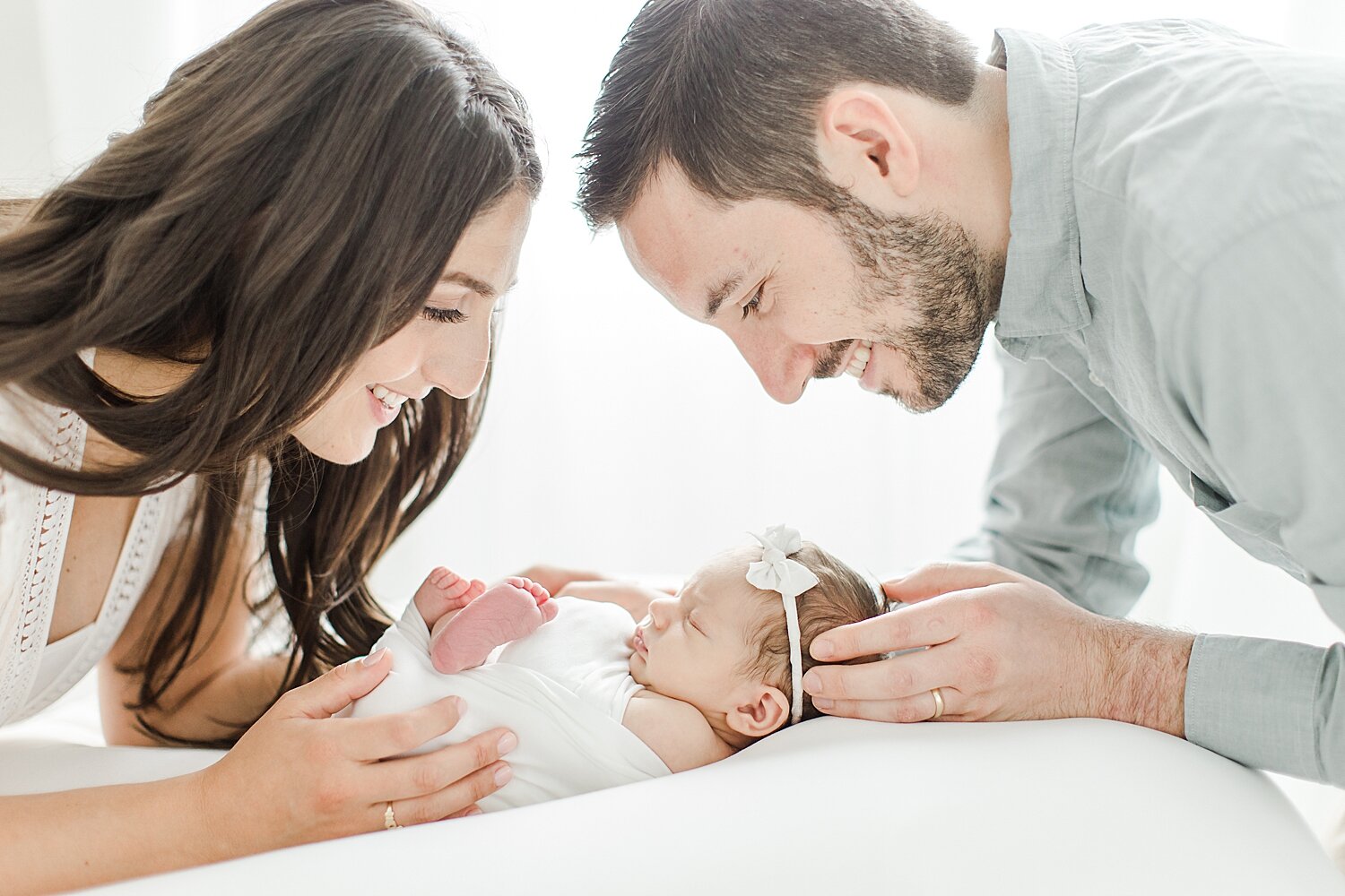 Mom and Dad looking at their daughter during newborn session. Photos by Kristin Wood Photography.
