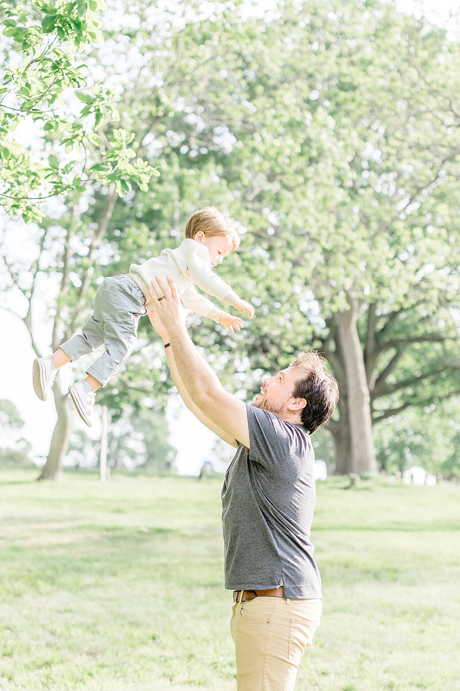 Dad throwing toddler son up in the air for photos with Kristin Wood Photography