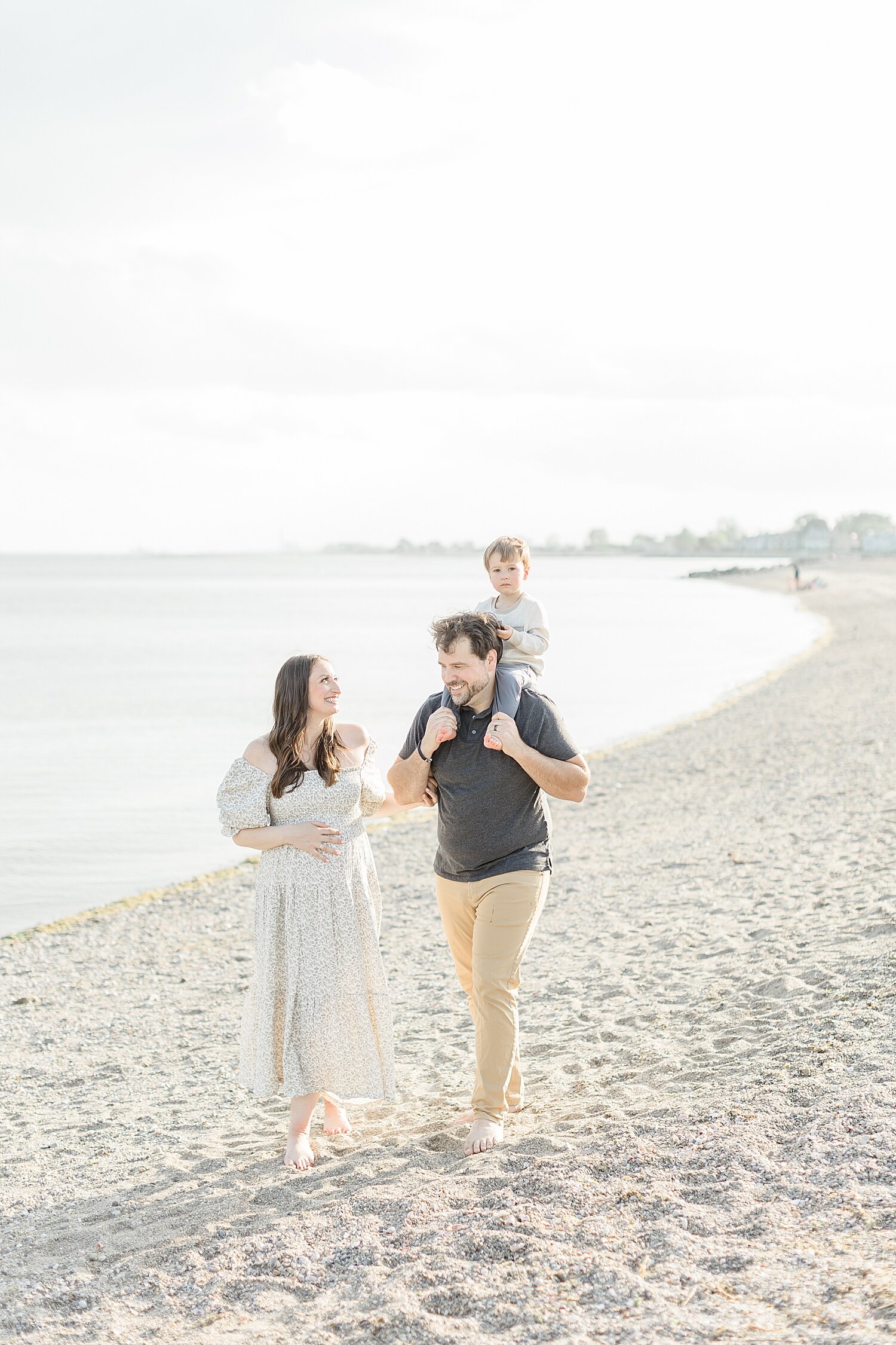 Mom and Dad walking down the beach with son on Dad's shoulders. Photo by Kristin Wood Photography.
