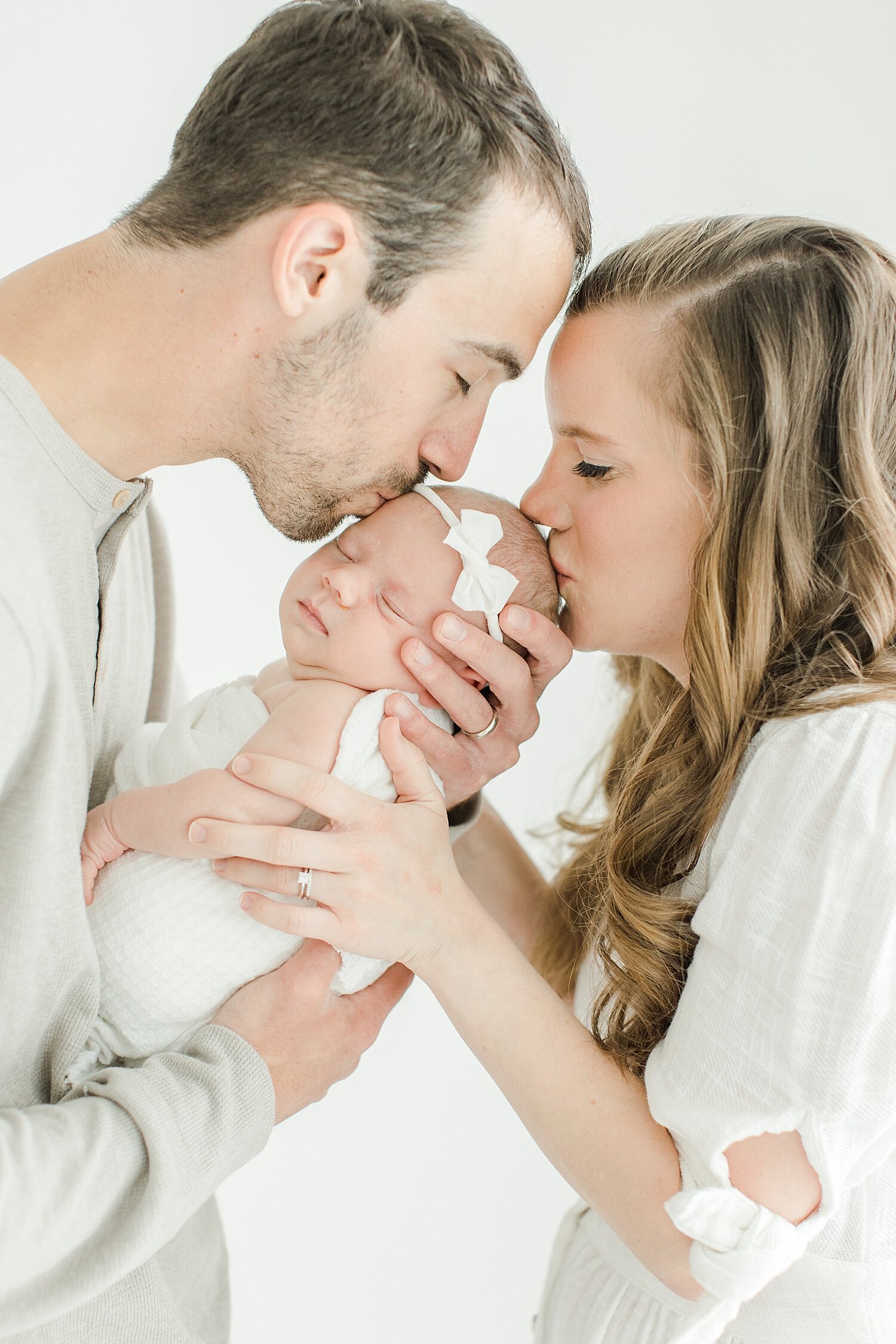 Mom and Dad kissing their baby girl during newborn photos with Kristin Wood Photography in Westport, CT.
