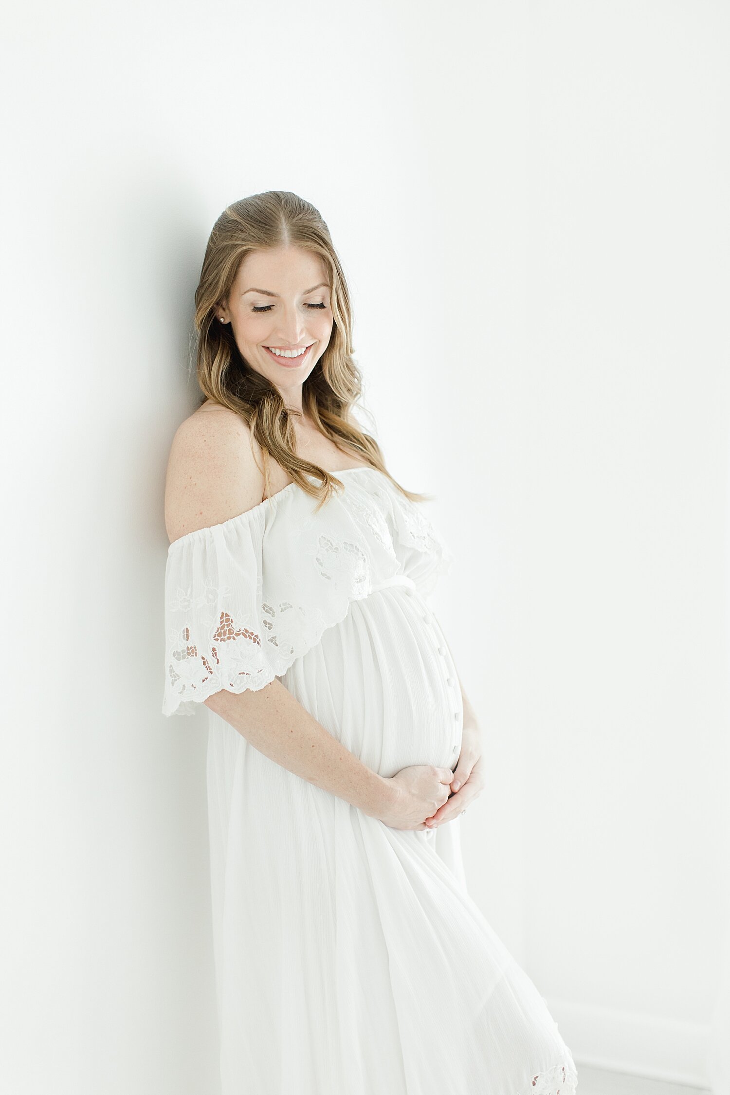 Mama-to-be wearing white fillyboo maternity dress for photos in studio with Kristin Wood Photography.