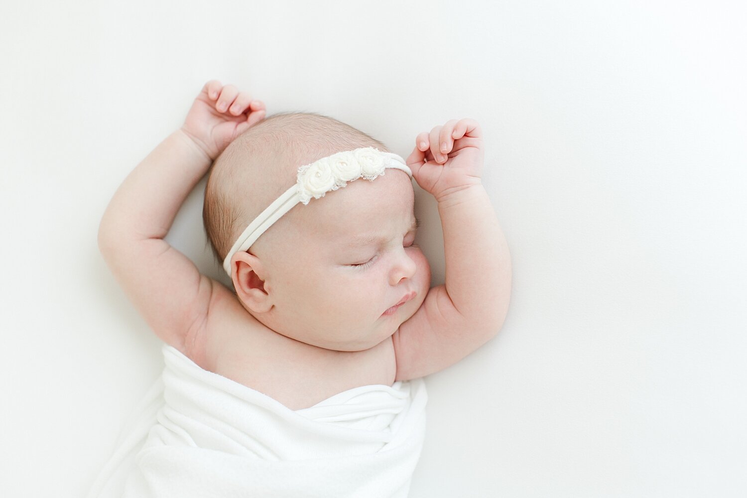 Baby girl sleeping with arms up during newborn photos with Kristin Wood Photography.