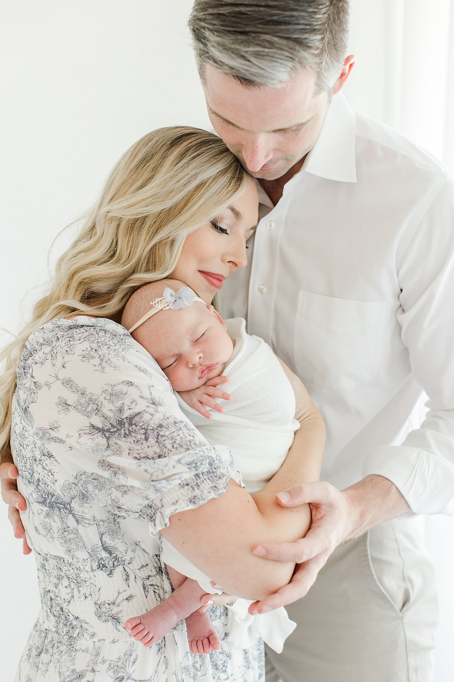 Mom and Dad snuggling their daughter for photos with Kristin Wood Photography.