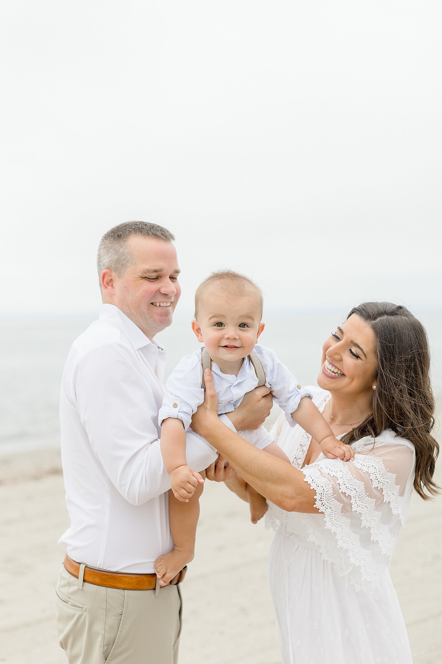 Mom and dad playing airplane with son on the beach for one year old photoshoot | Kristin Wood Photography