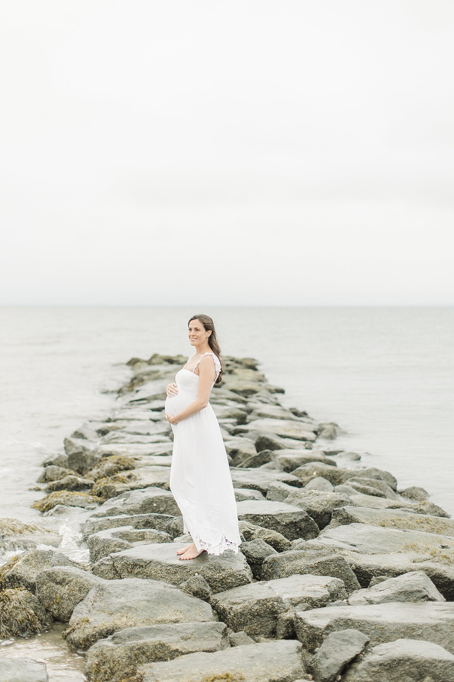 Pregnant mom standing on rocks at Sherwood Island | Kristin Wood Photography