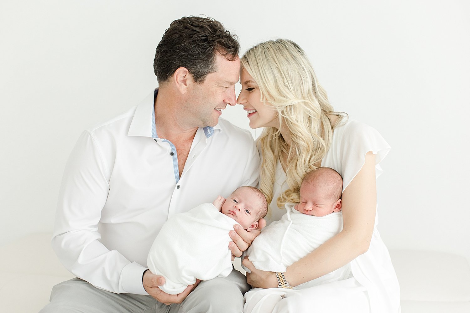 Mom and Dad holding their twin boys at newborn session with Kristin Wood Photography.