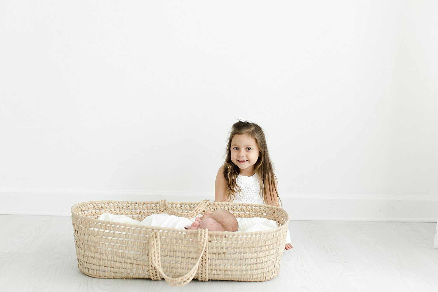 Big sister looking over her baby brothers in Moses basket | Kristin Wood Photography