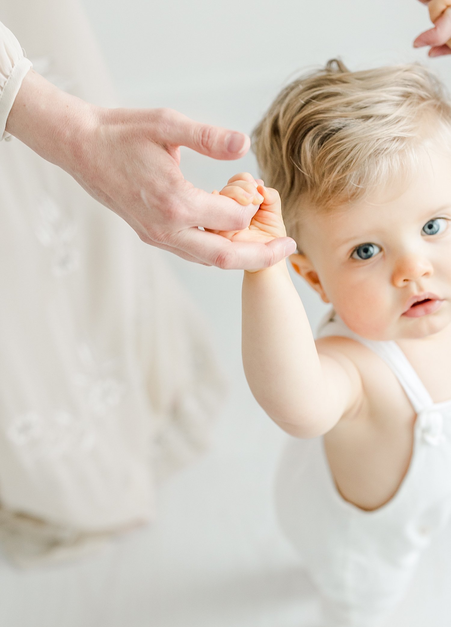 One year old holding Mom's hands looking up with big blue eyes | Kristin Wood Photography