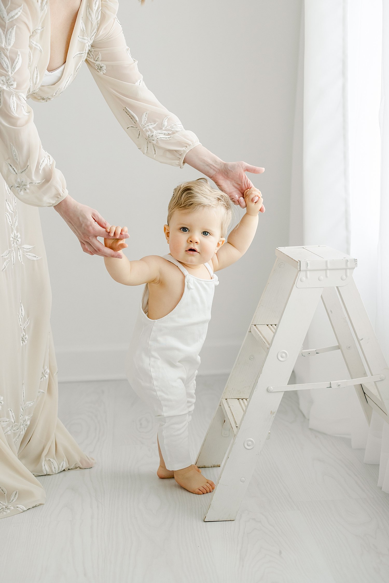 One year old little boy holding Moms hands standing by ladder | Kristin Wood Photography