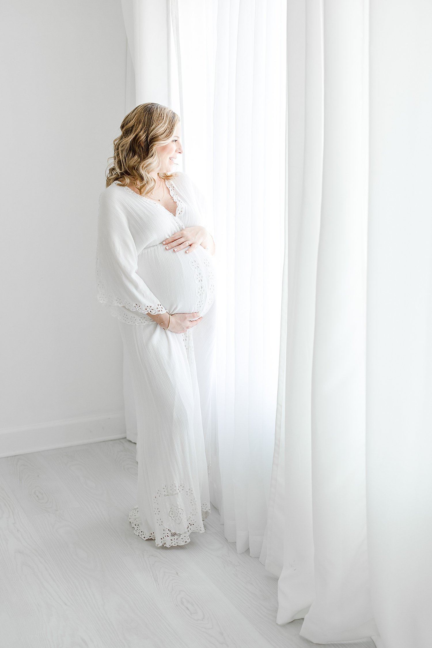 Mom looking out window during maternity session | Kristin Wood Photography
