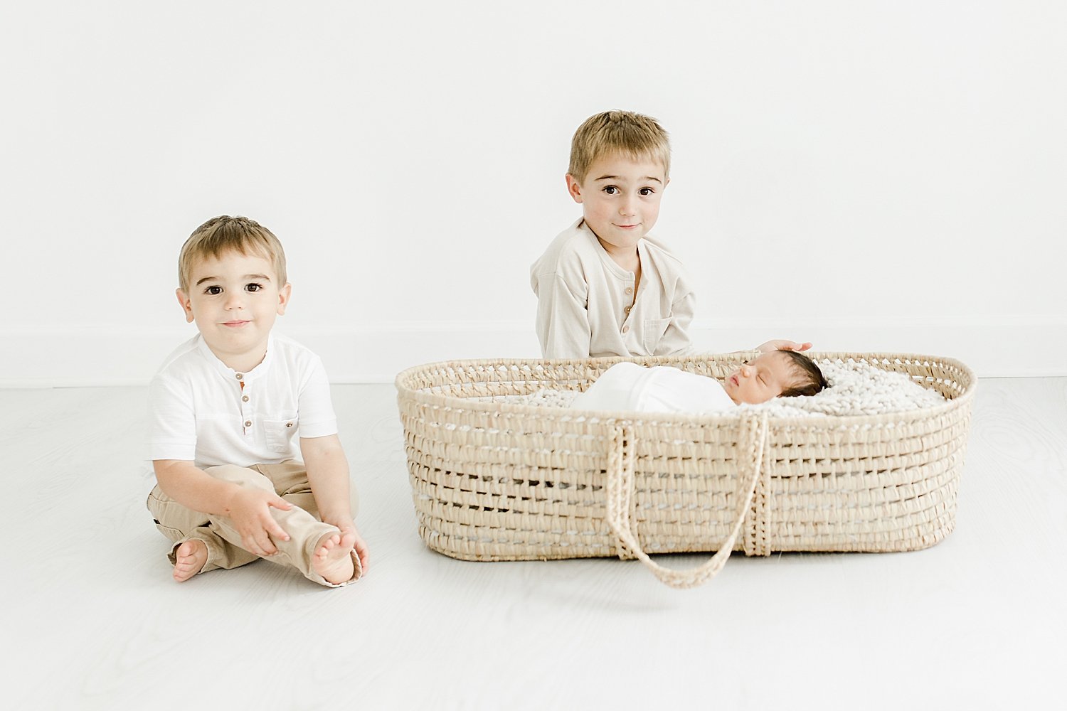 Two big brothers looking over baby brother in Moses basket | Kristin Wood Photography